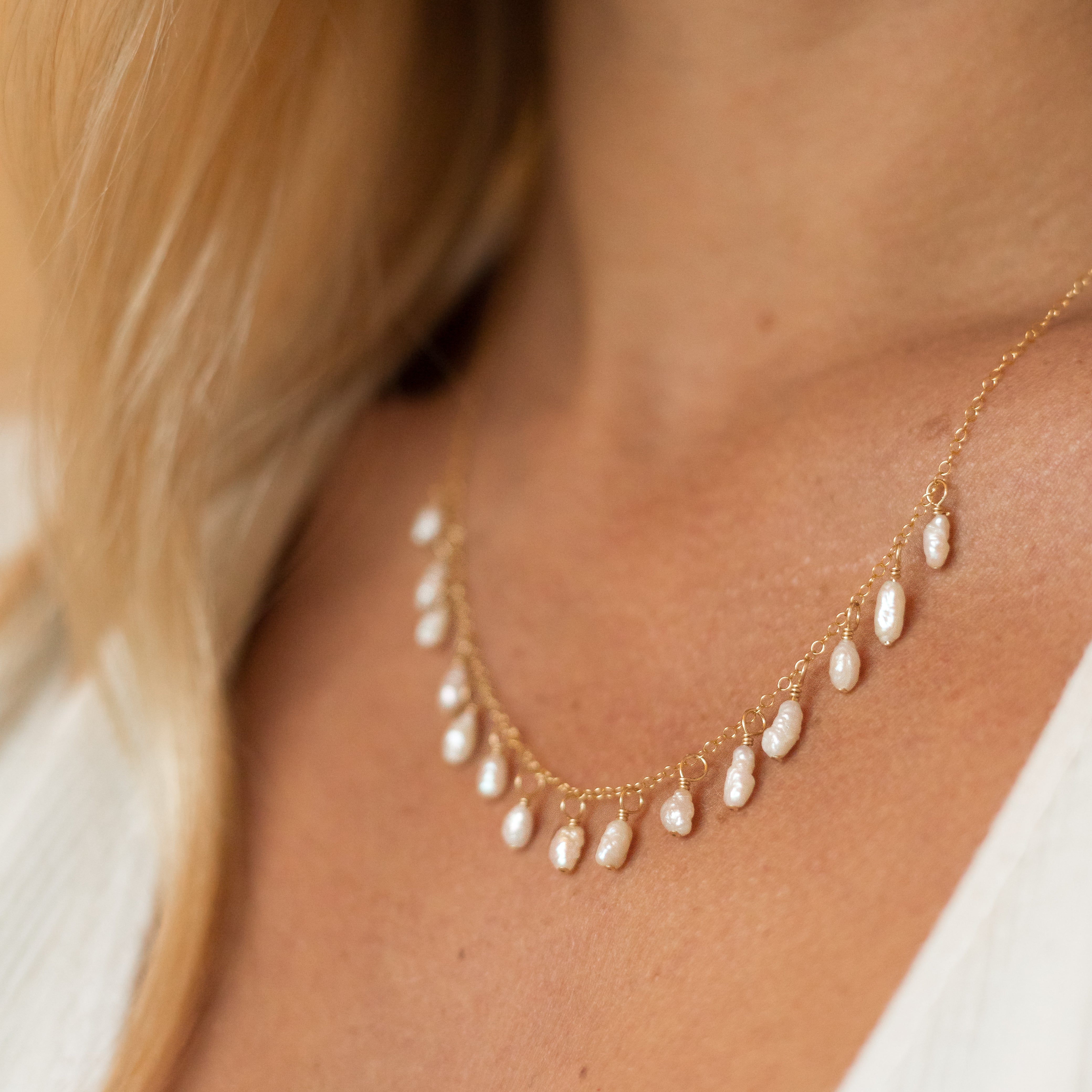 Gold chain with 15 pea sized freshwater pearls attached to it. Shown on a woman's neck.