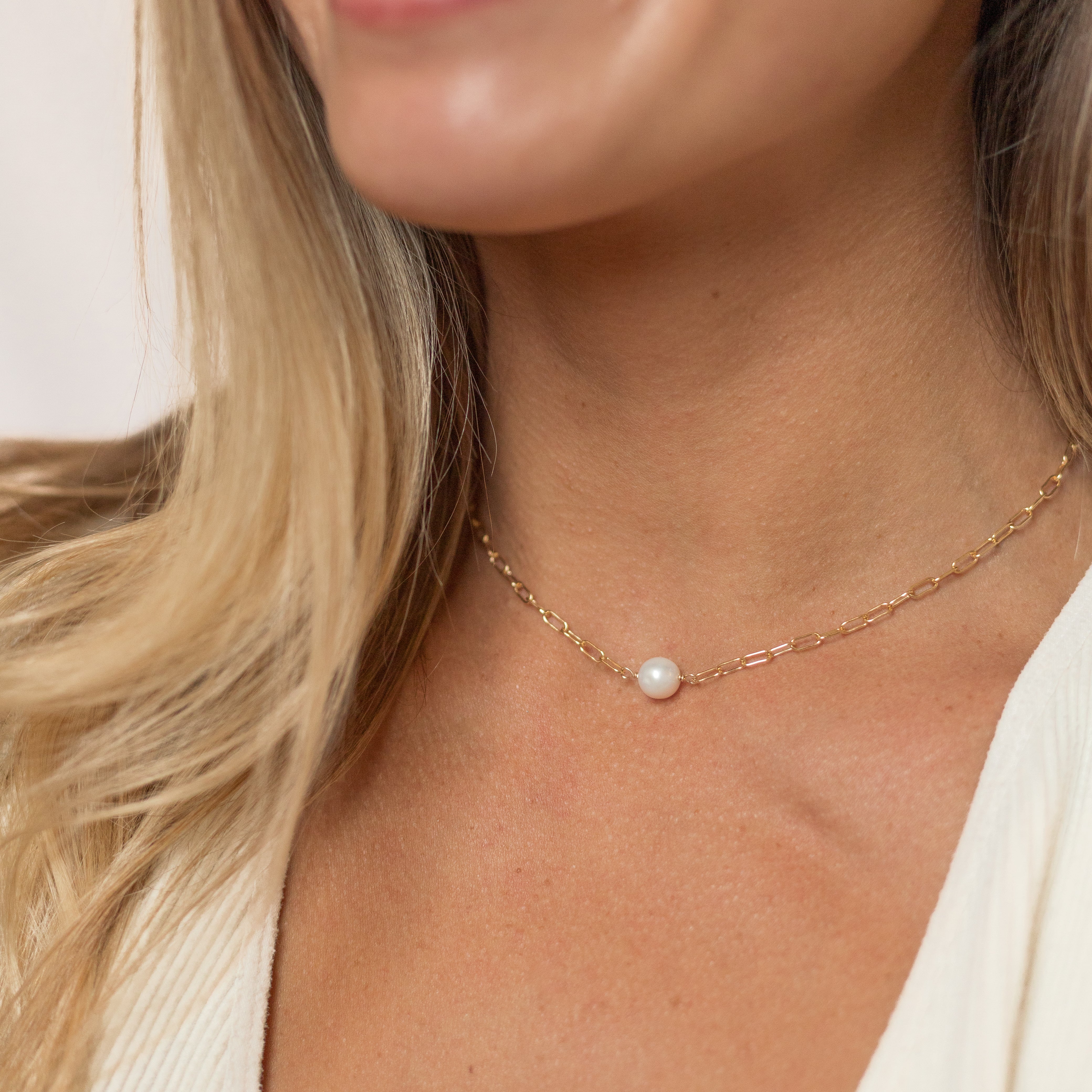 Small pearl wire wrapped onto our gold mini paperclip chain. Shown on a woman’s neck.