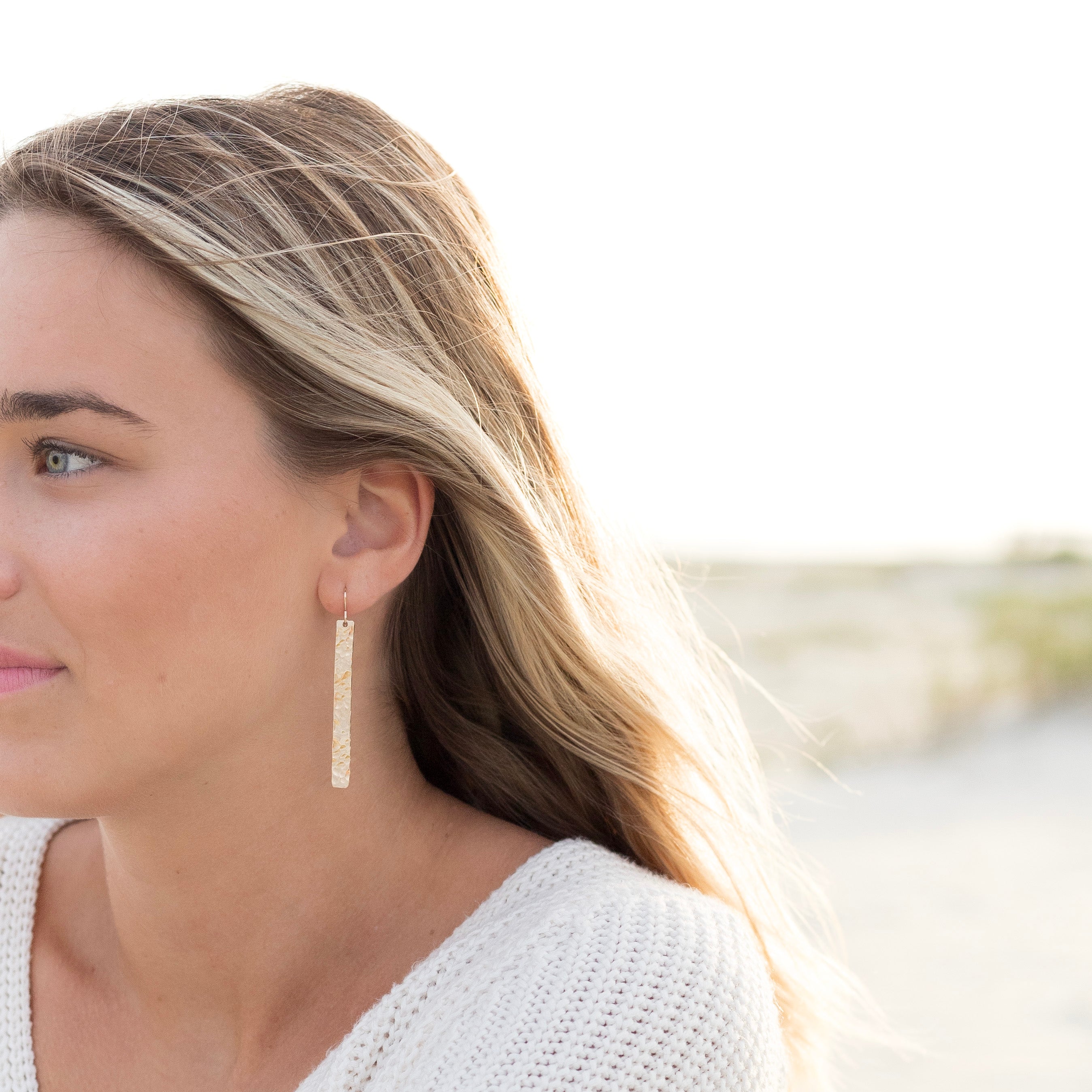 Two inch long gold filled bar earrings shown in a woman's ear.