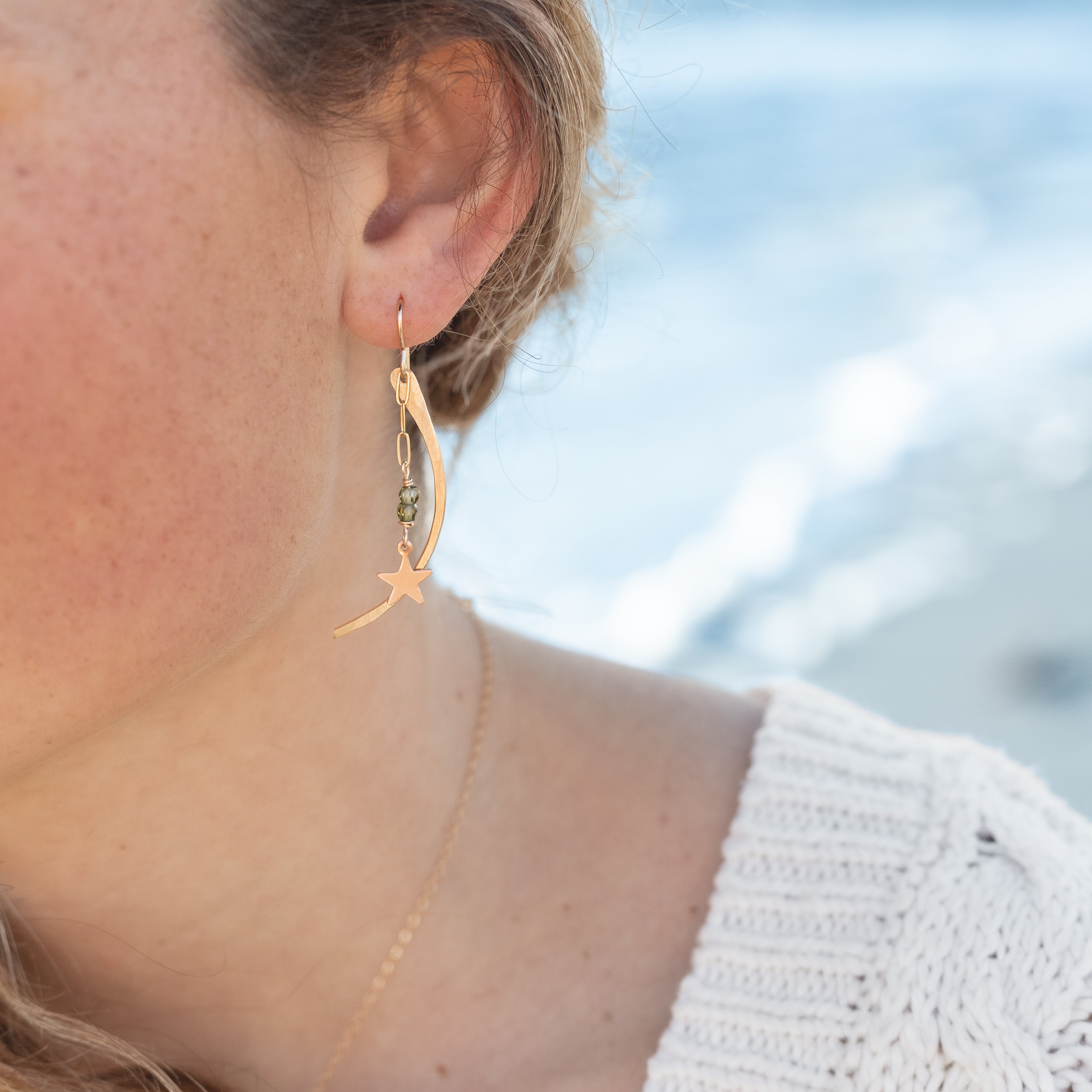 14k gold-filled moons with rose gold stars and green garnet hanging from gold chain. On gold-filled ear wire. About 2" in length. Shown in a woman’s ear.