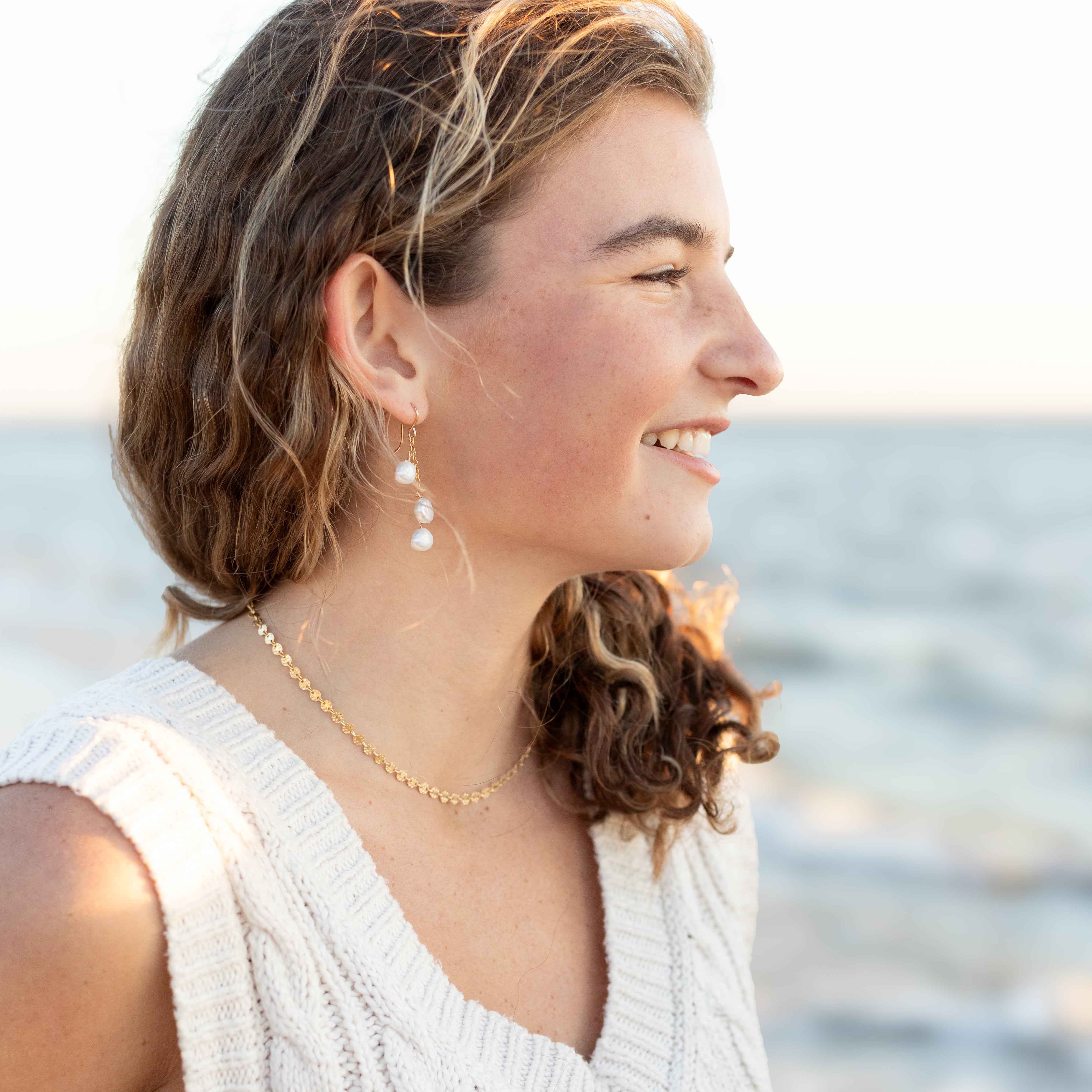 1 1/2 inch long, pearl waterfall earrings with gold chain shown in a woman’s ear.