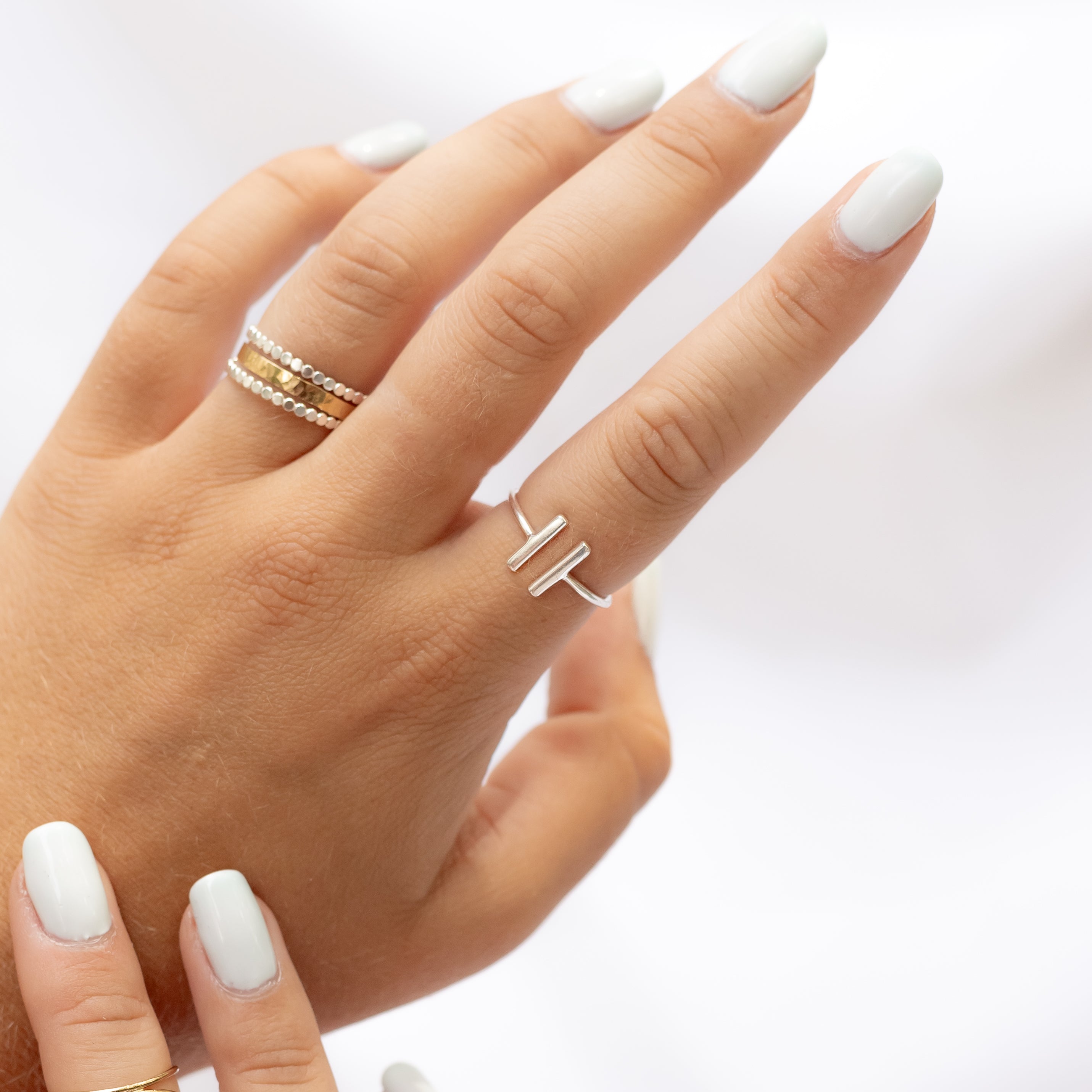 Sterling silver double bar ring shown on a woman's pointers finger.
