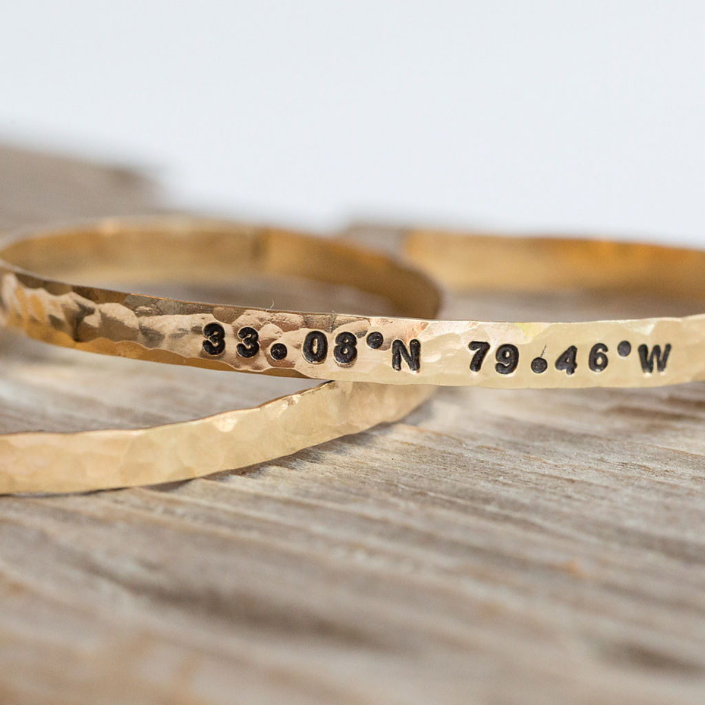 Coordinates stamped on the outside of a gold cuff. 