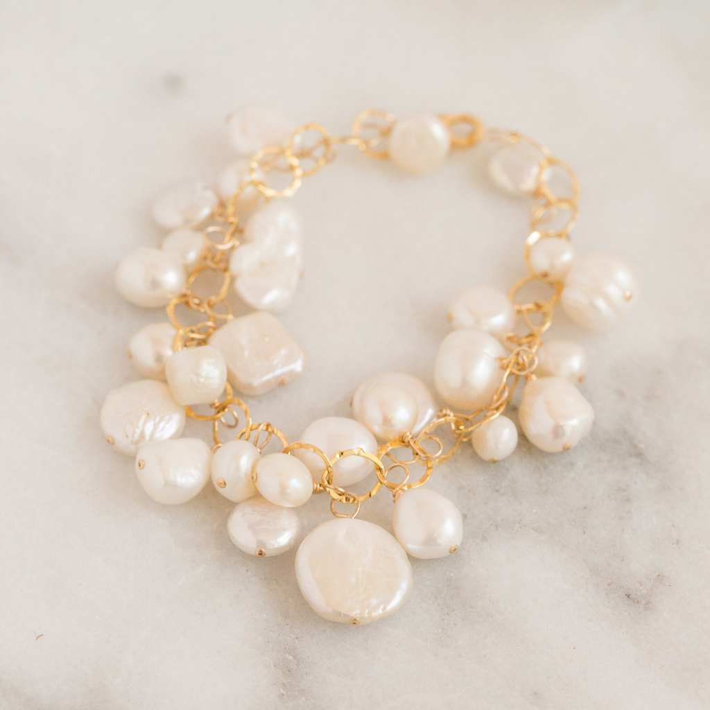 large gold circle chain bracelet with freshwater pearls wire wrapped onto each loop.