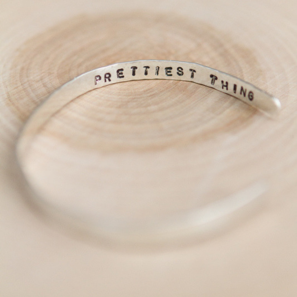 the phrase "Prettiest Thing" stamped on the inside edge of a sterling silver cuff.