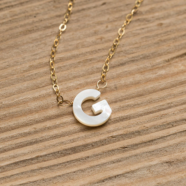 Mother of pearl initial "G" on a gold chain.