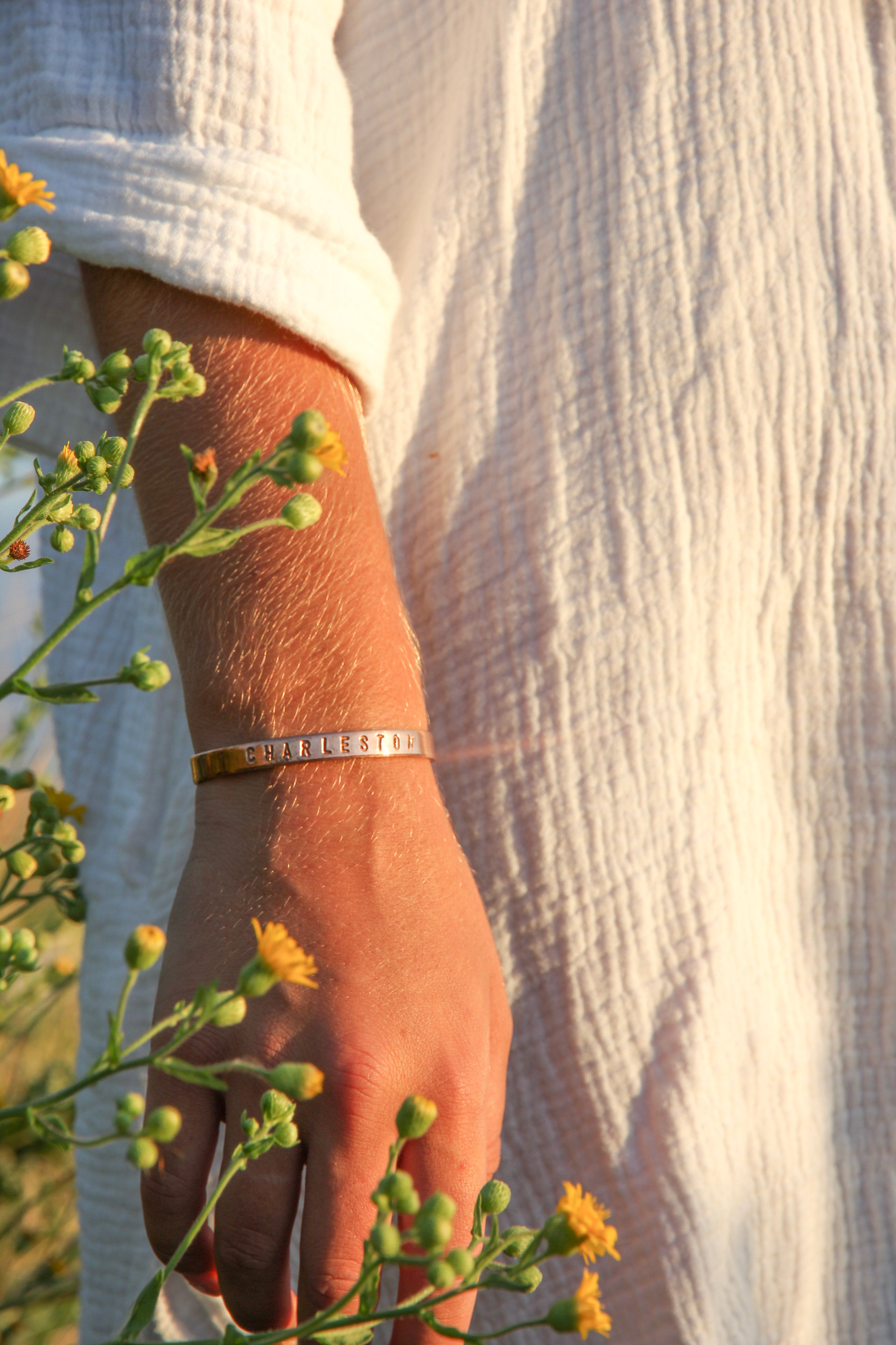 "Charleston" stamped with large letters on the outside of one of our copper cuffs. Shown on a woman's arm.