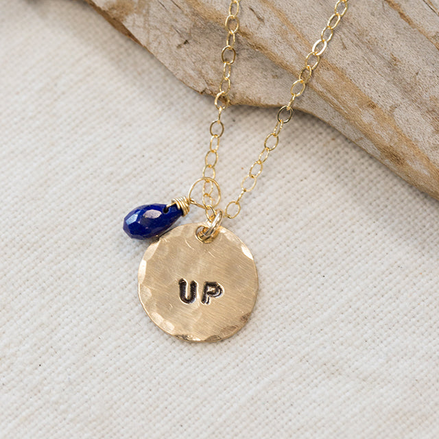 gold filled medium size circle (less than a dime) with the word "up" stamped on it and a blue bead on a gold chain
