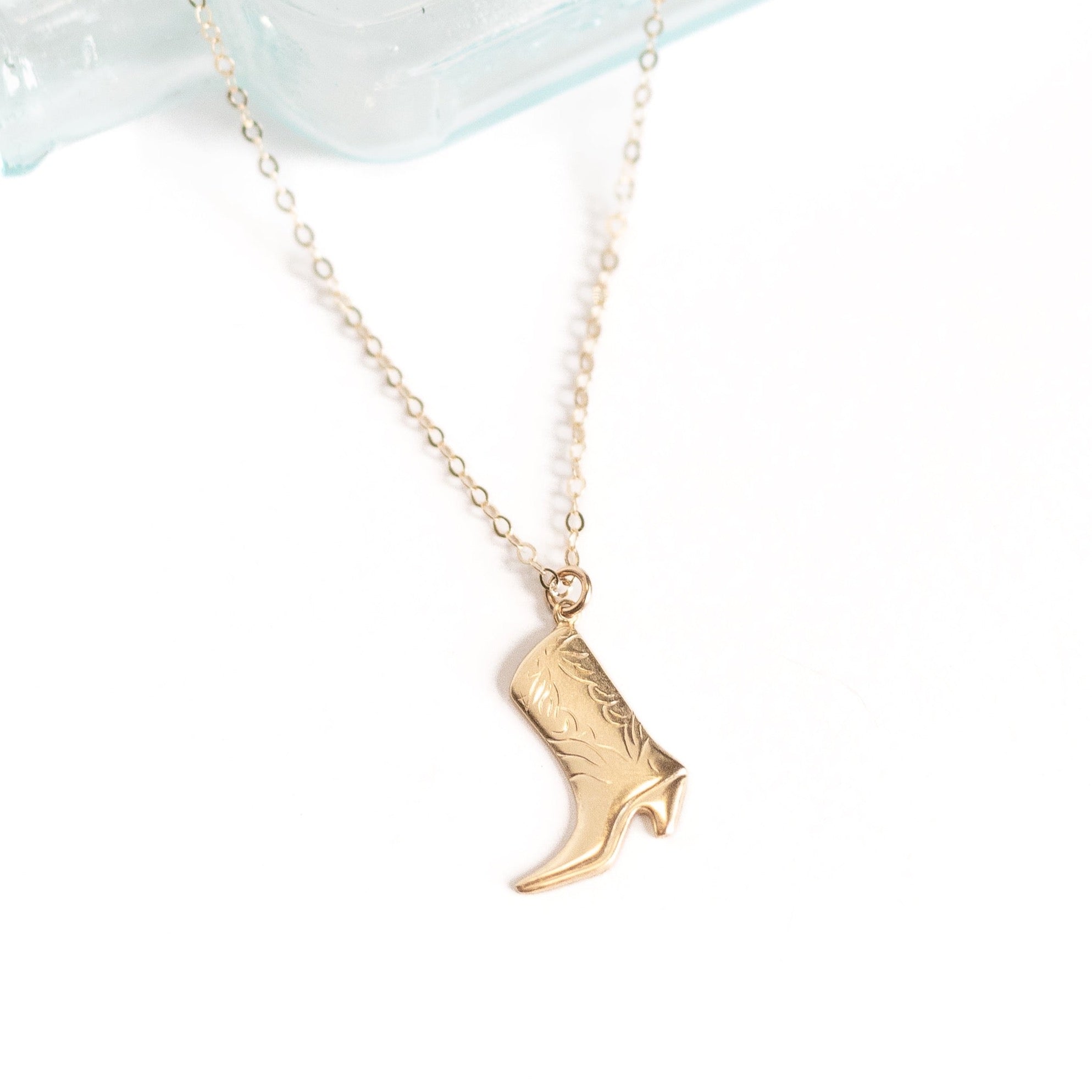 A little less than one inch long gold cowgirl boot charm attached to a gold chain.