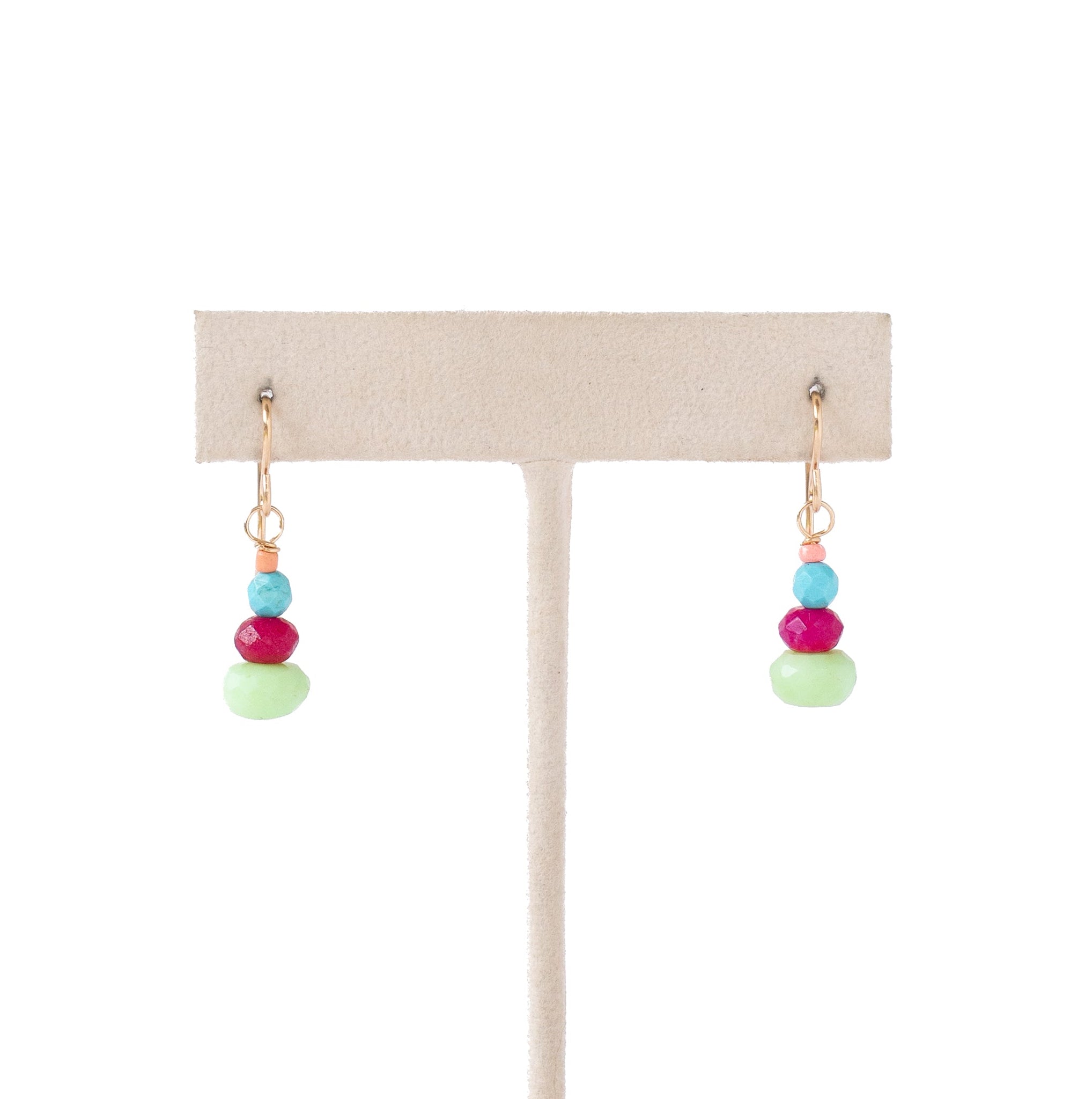 A pair of dangling earrings displayed on a beige jewelry stand against a white background. Each earring has small gold-tone hooks with stacked beads in turquoise blue, magenta pink, and light mint green.