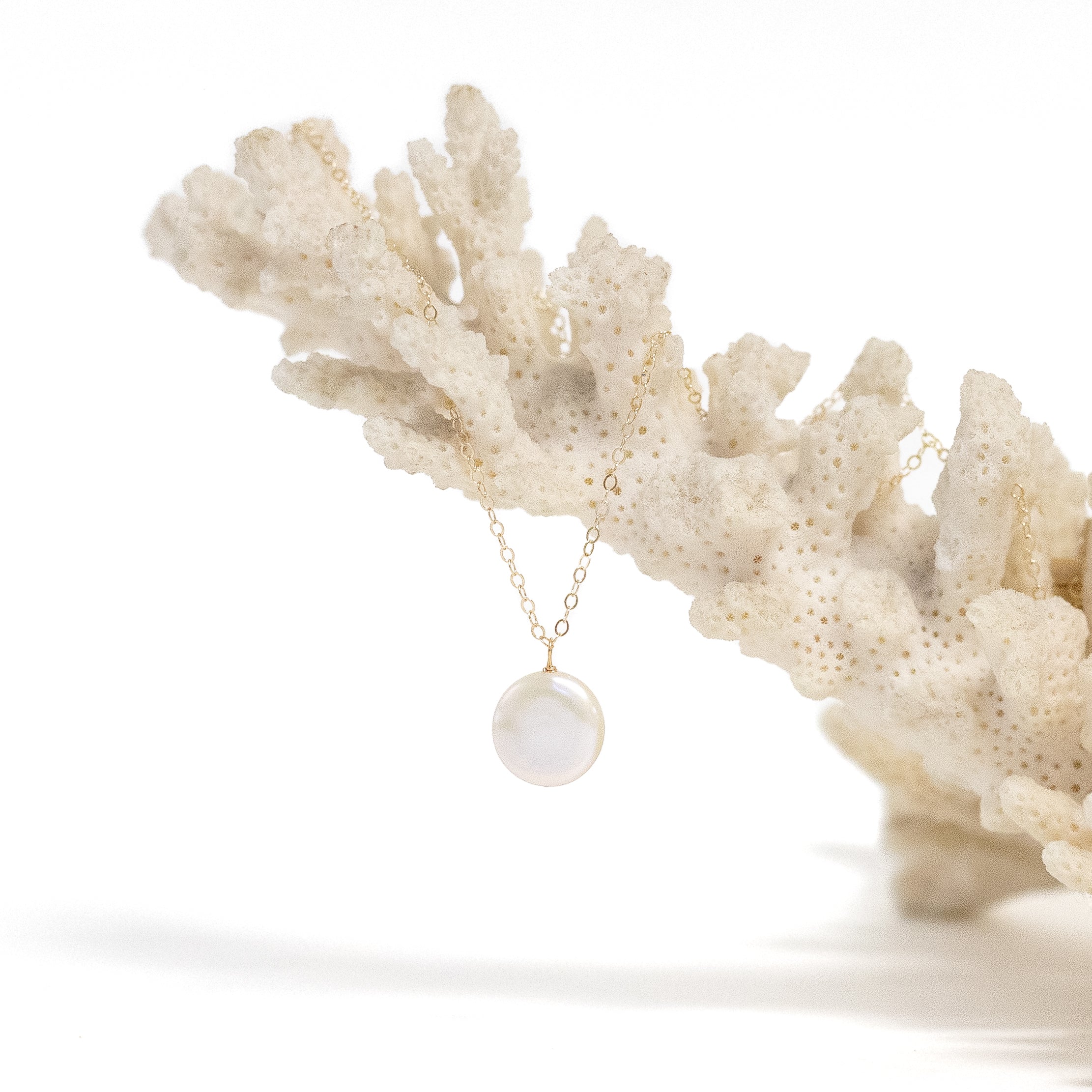 Freshwater coin pearl attached to our basic simple gold chain. Shown on coral. 