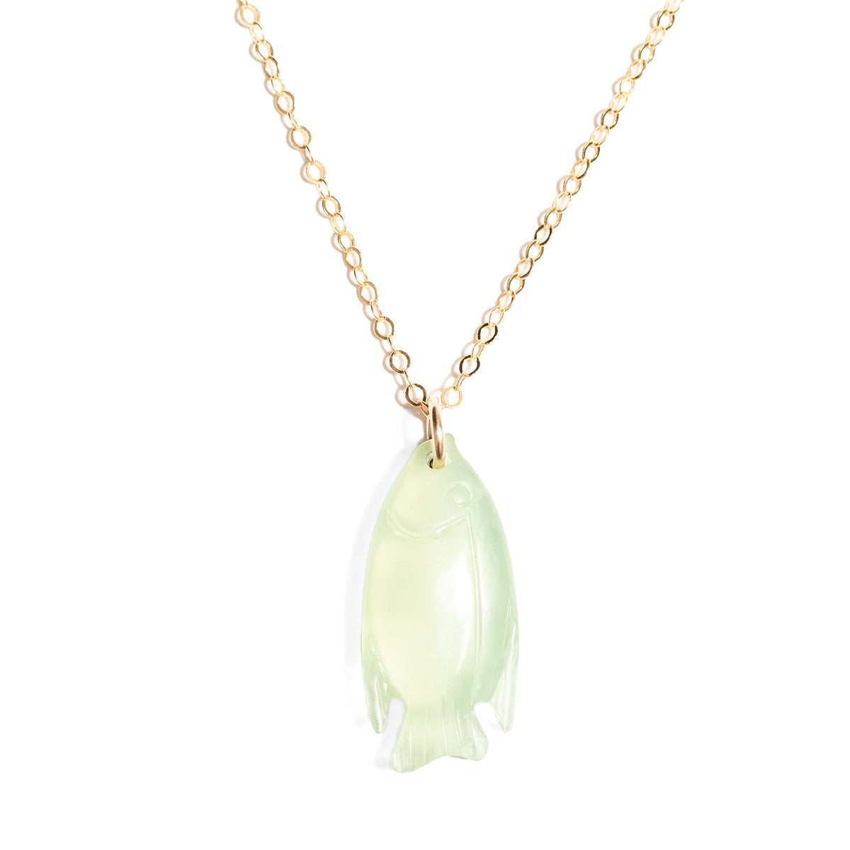 A delicate gold chain necklace featuring a carved pale green jade pendant shaped like a fish, shown against a solid white background.