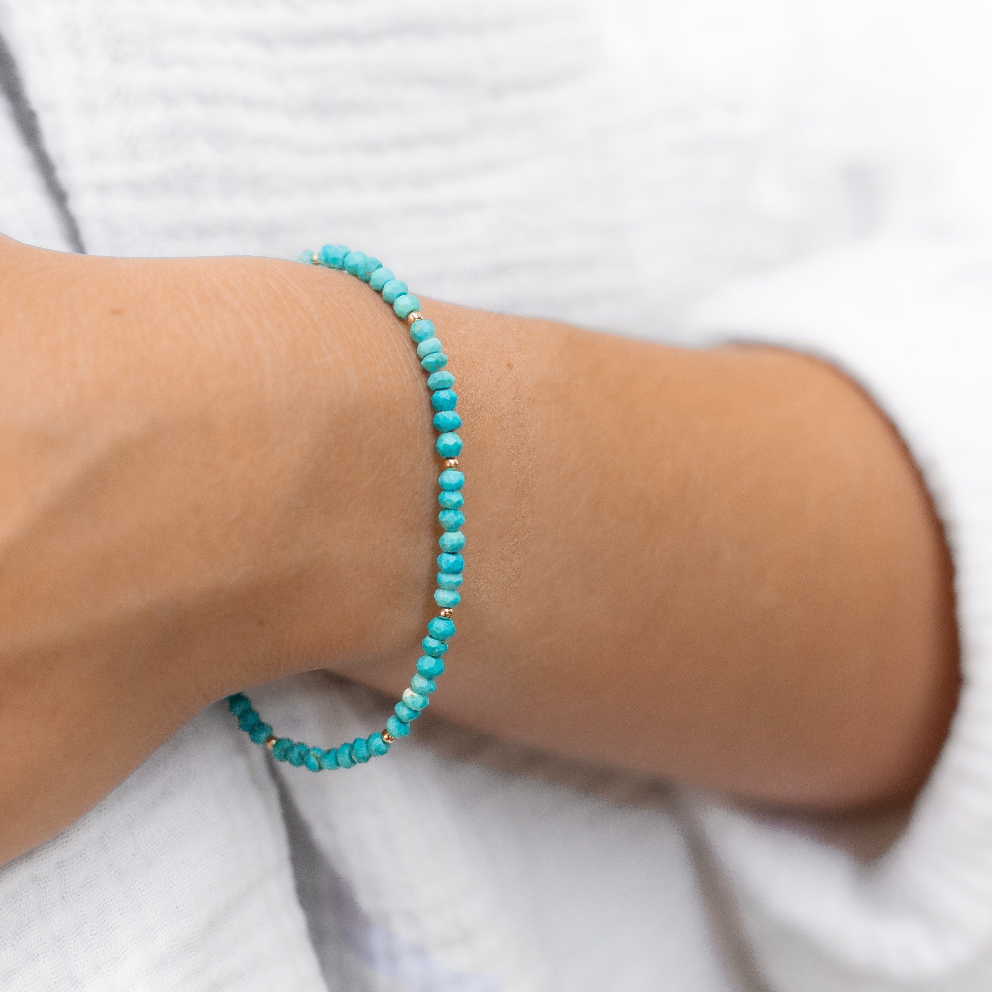 Turquoise beaded bracelet with gold filled beads every seven beads. Shown on a woman’s wrist 