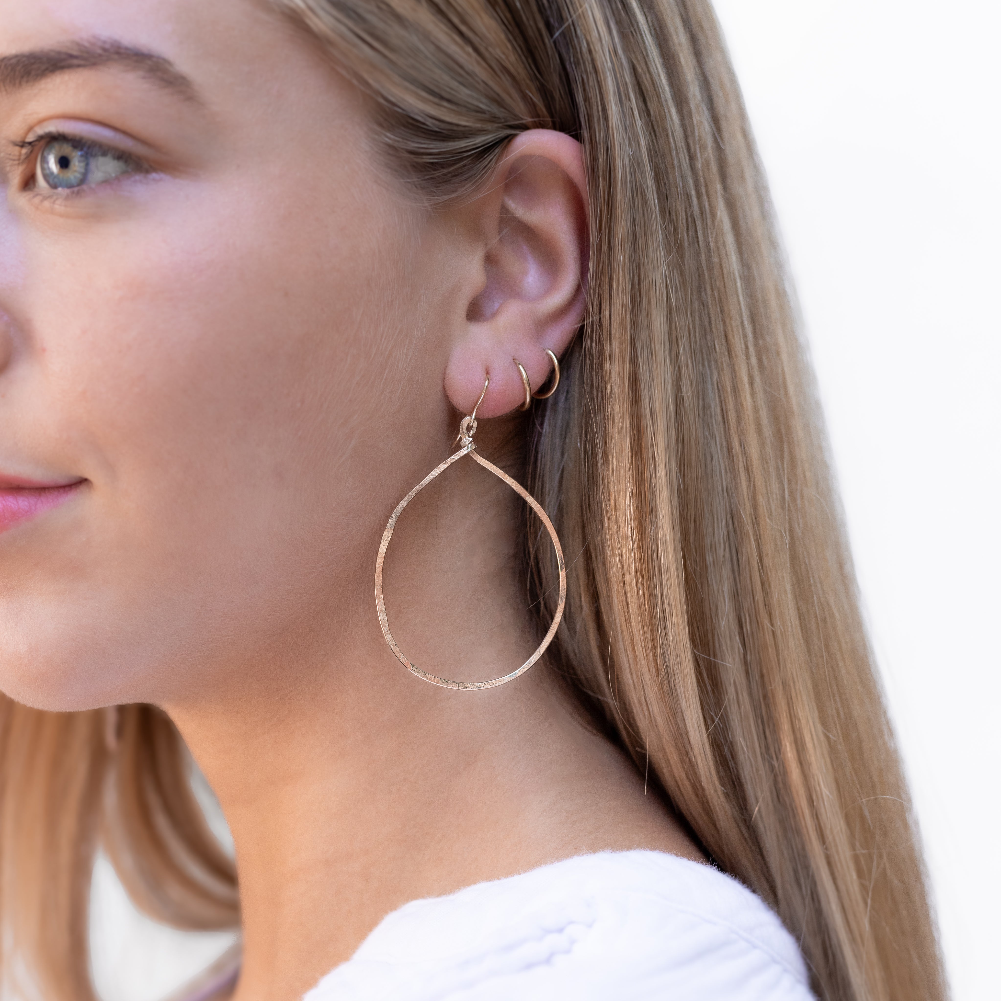 Hand forged medium gold filled hammered hoops shown in a woman’s ear