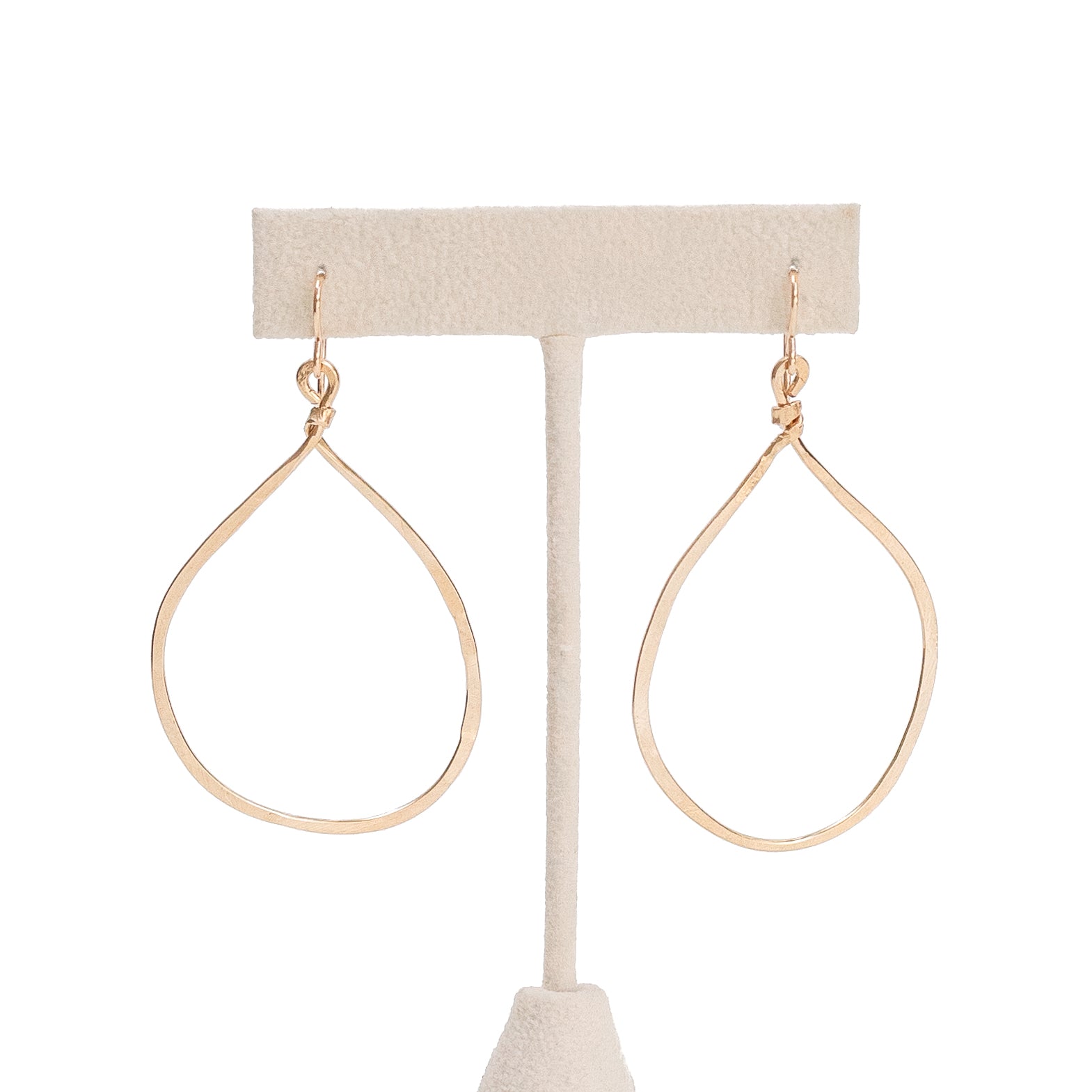 Hand forged hammered gold hoops hanging from an earring post. 