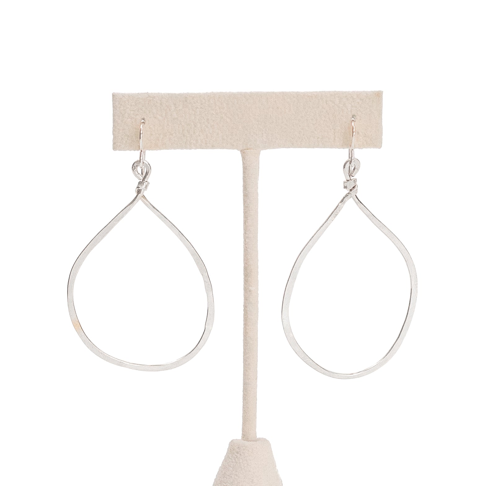 Hand forged hammered silver hoops hanging from an earring post 