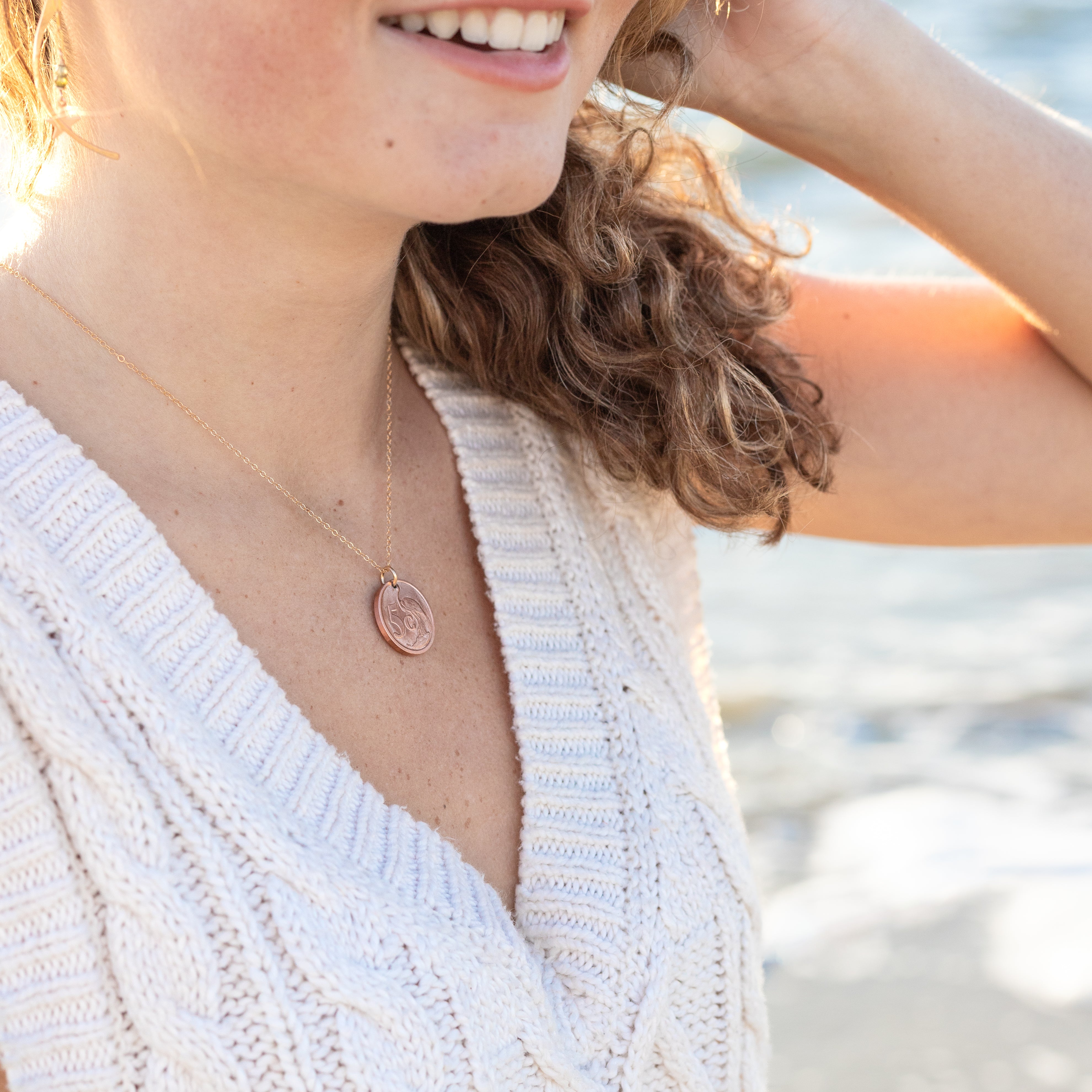 Copper coin on a gold chain around a woman’s neck. 