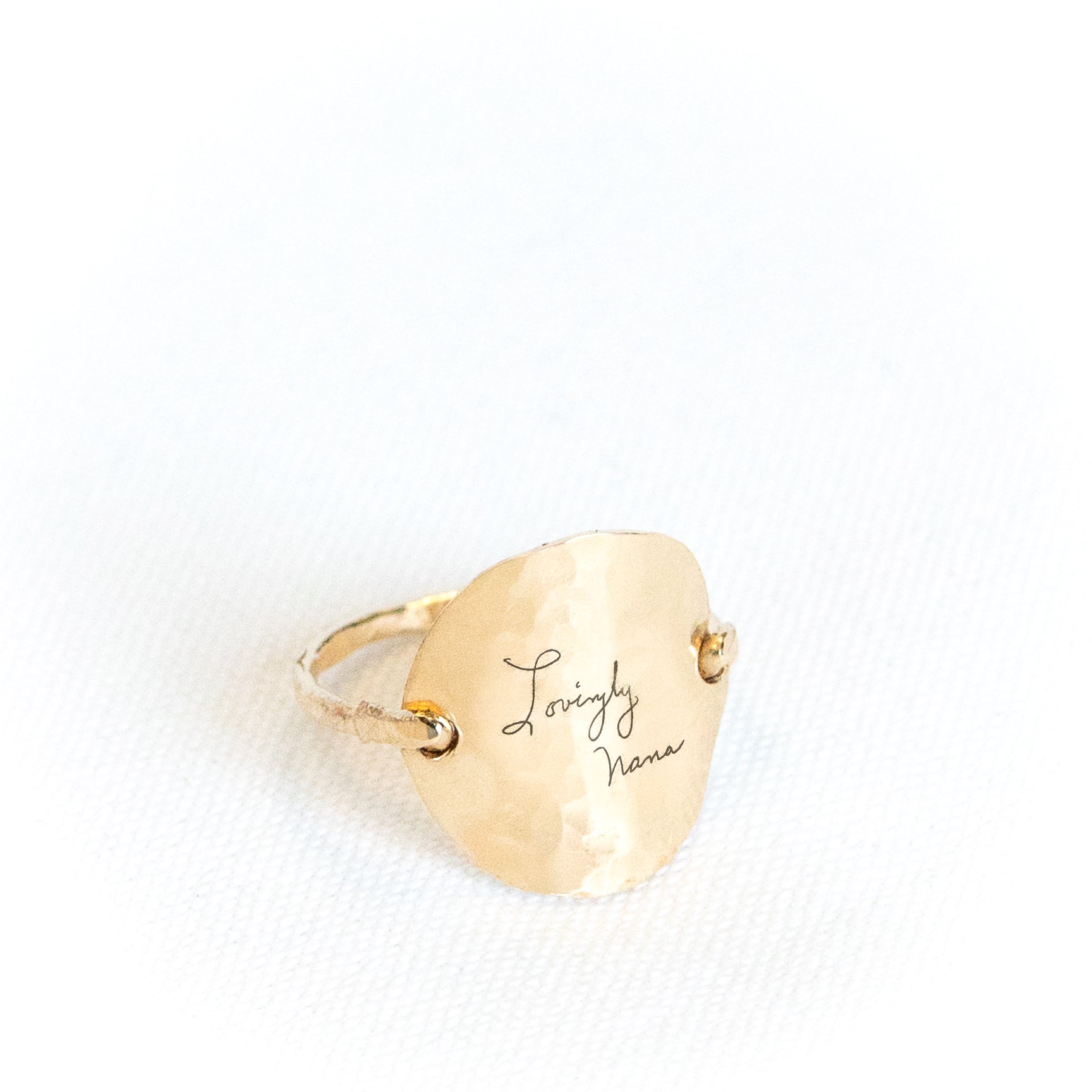 Gold ring with 'Loveingly Nana' engraving on a white background