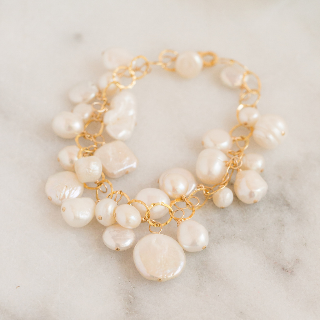 large gold circle chain bracelet with freshwater pearls wire wrapped onto each loop. 