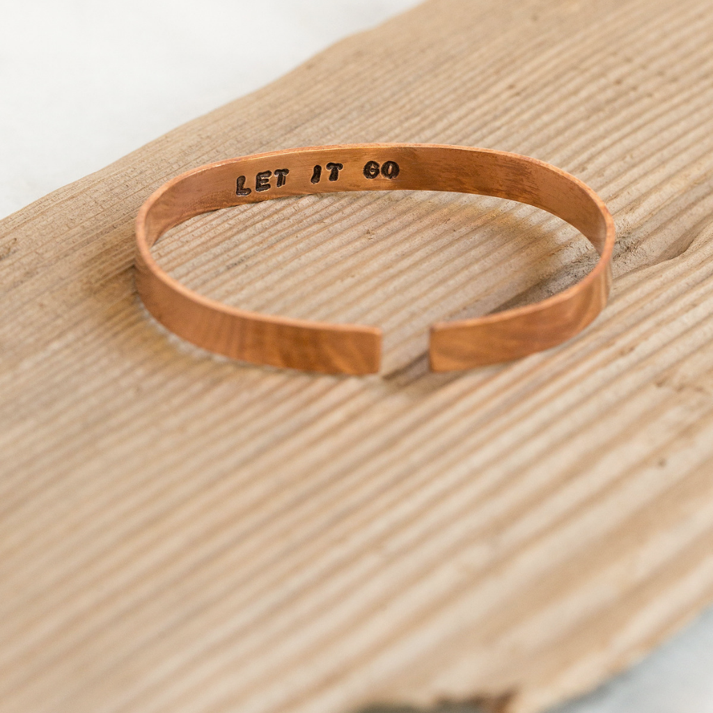 The phrase "Let it go" stamped on the inside of one of our copper cuffs. 