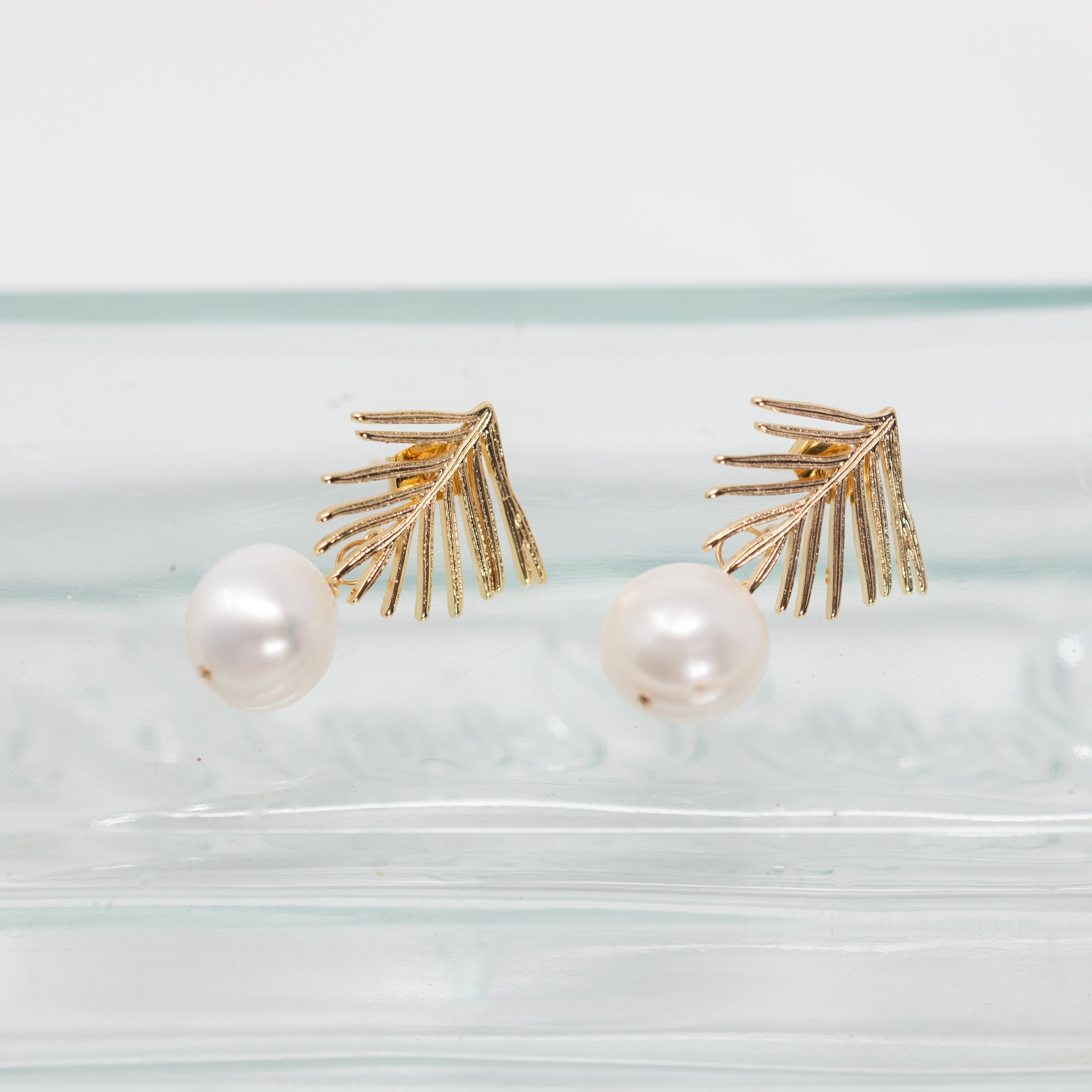 Gold plate palm studs  with a pearl wire wrapped to the bottom. 