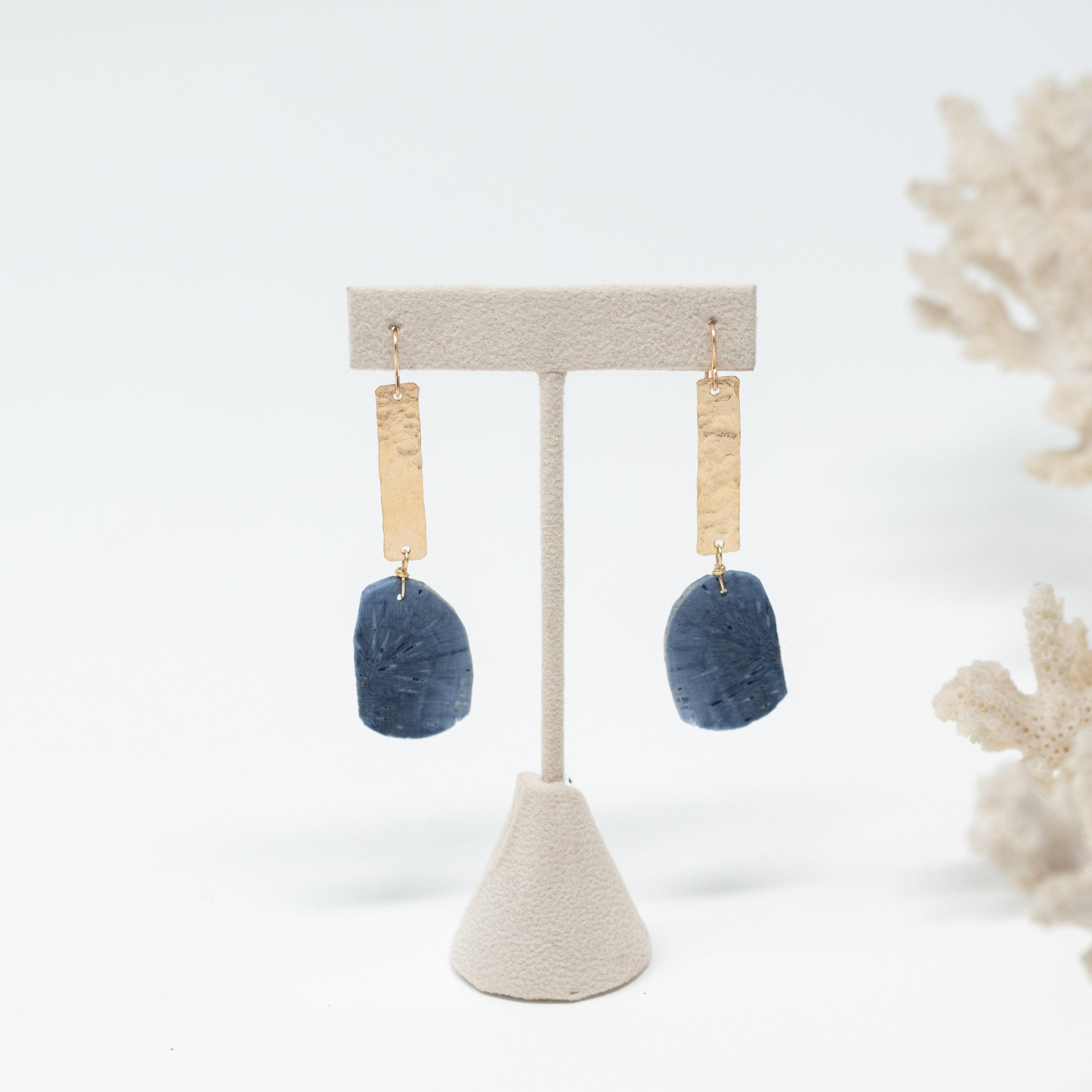 A pair of gold vertical bar earrings with a nickel sized piece of blue sponge coral wire wrapped to the bottom of the gold bar. Around 1.5 inches long.
