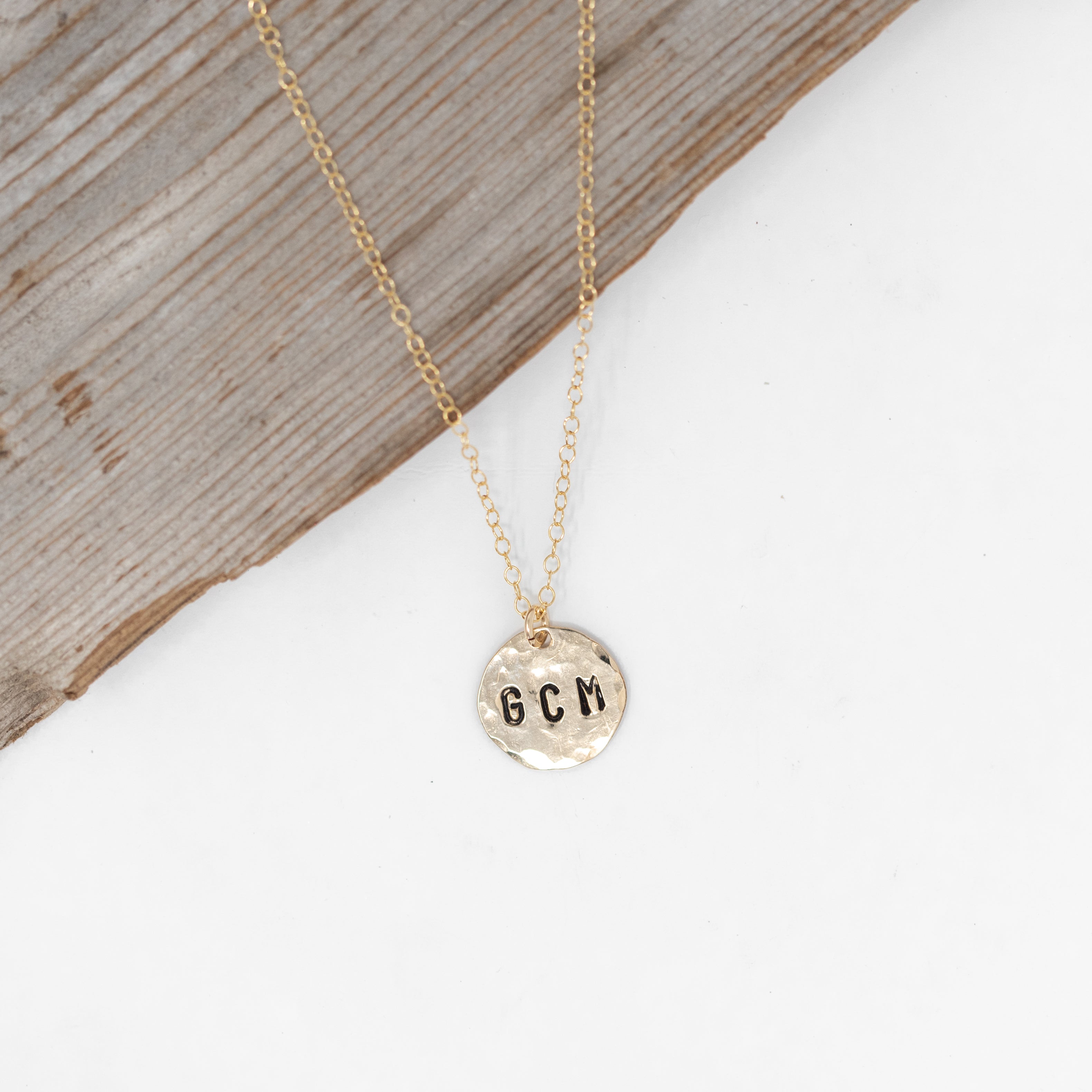 Medium size gold filled hammered circle with initials stamped onto it. On a gold chain.  