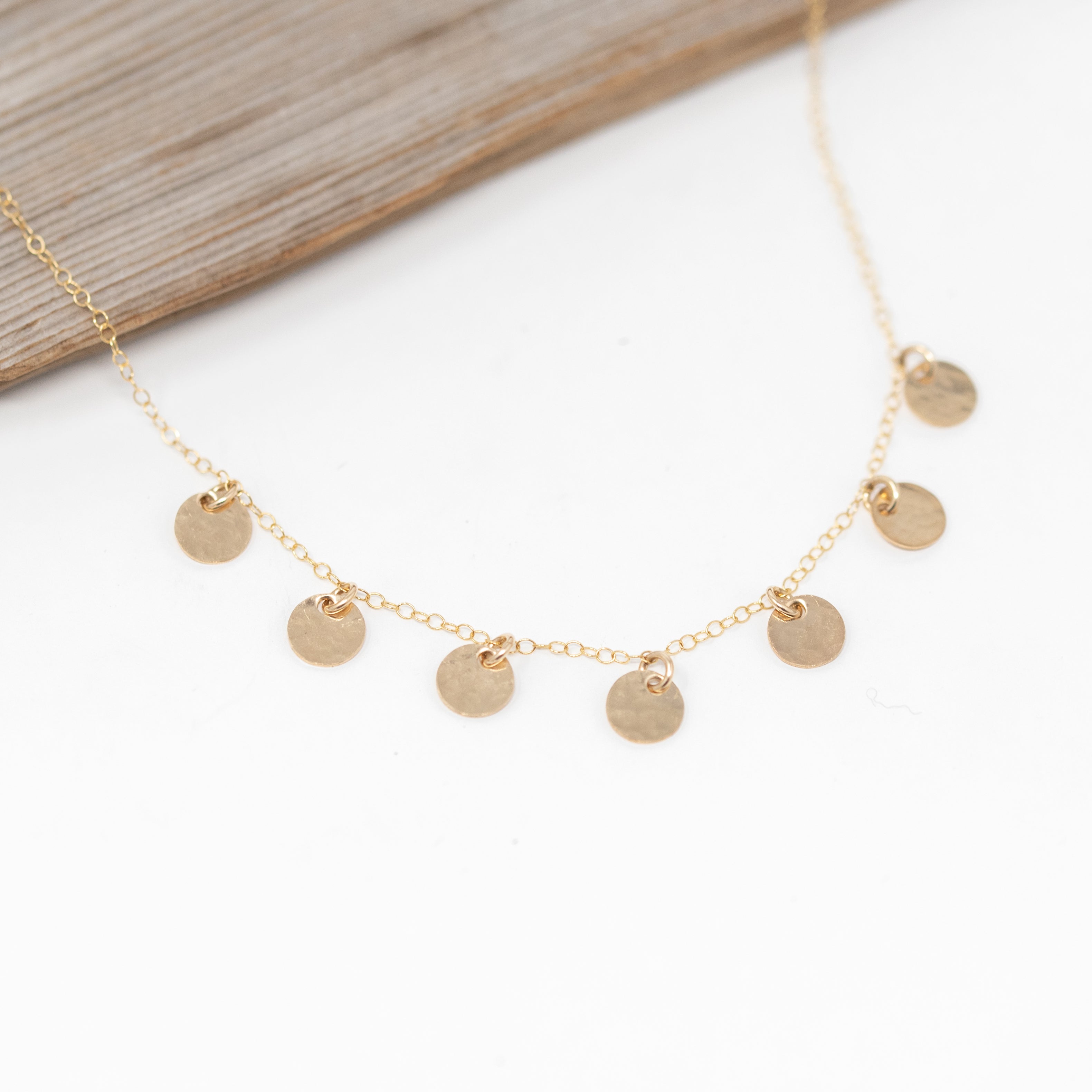 gold necklace with seven tiny circles attached to it. They are about a pea size and spaced about half an inch apart.