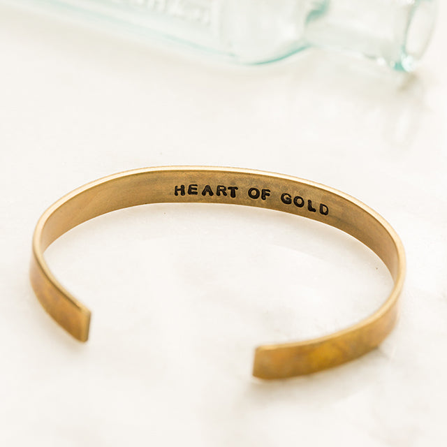 Brass cuff bracelet with phrases hand stamped on the inside of the bracelet filled in with black coloring