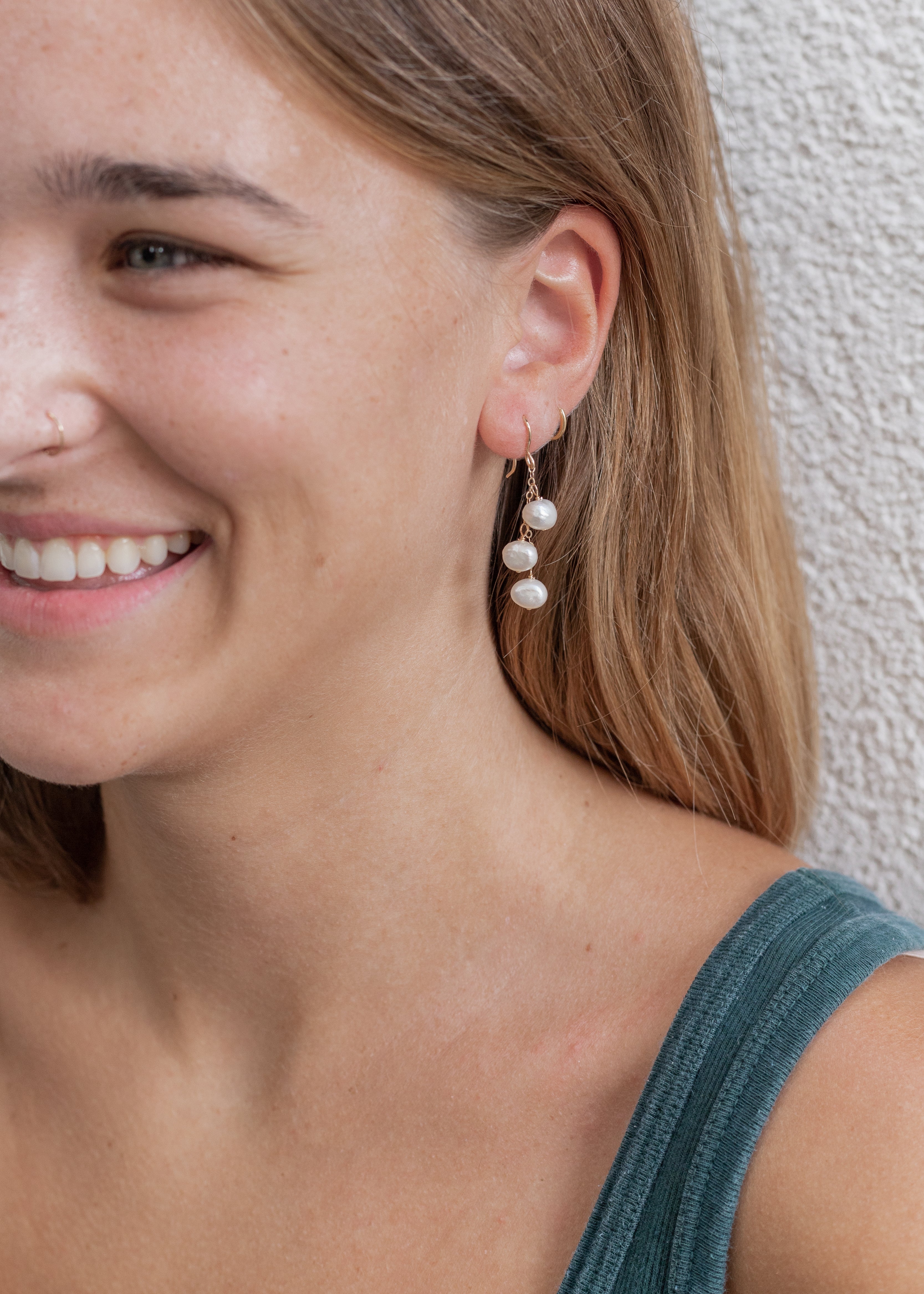 1.5 inch long earring with gold chain and pearls water-falling from the chain. Shown in a woman's ear. 