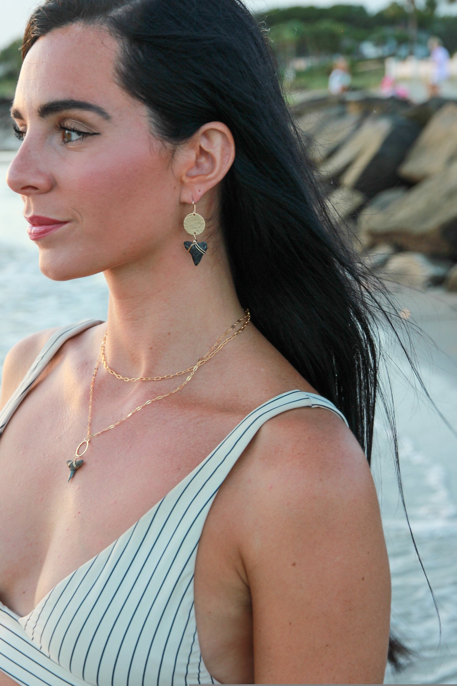 Gold filled hammered circle with a bull shark tooth attached to the bottom shown in a woman's ears.