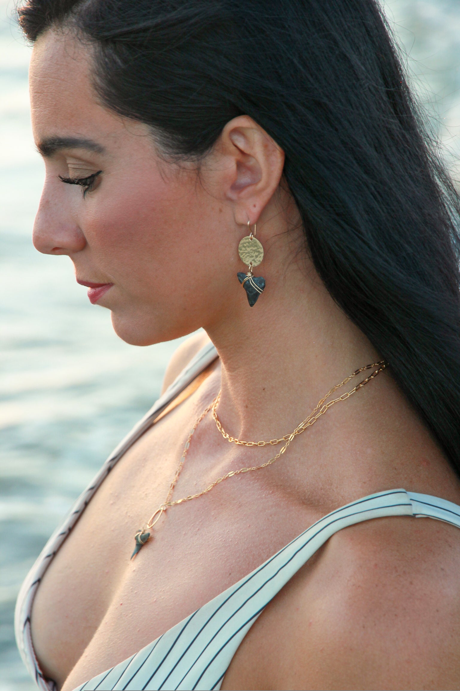 Gold filled hammered circle with a bull shark tooth attached to the bottom shown in a woman's ears. 