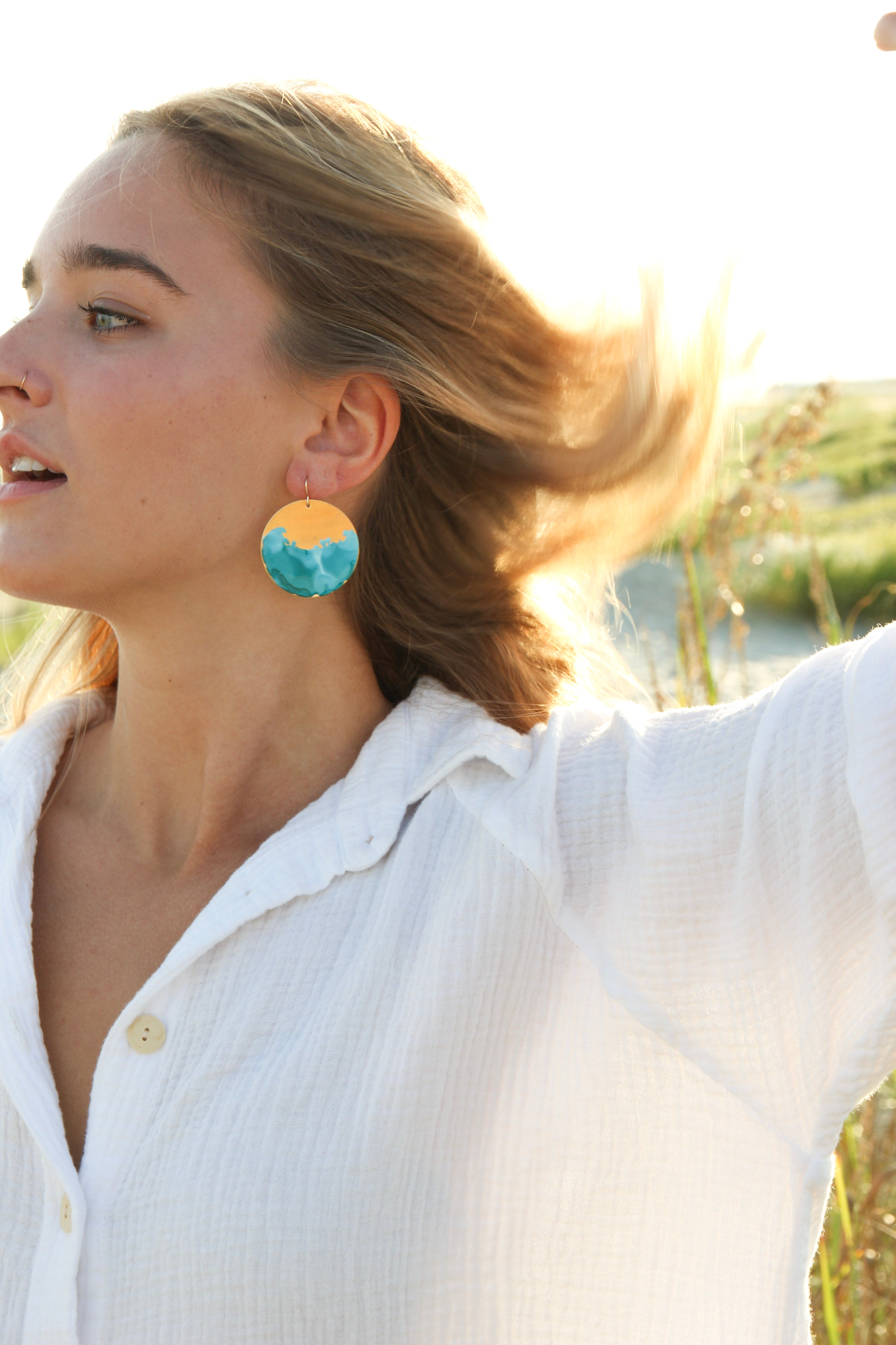 Brass circle earrings hand painted to be blue.  Shown in a woman's ear. 