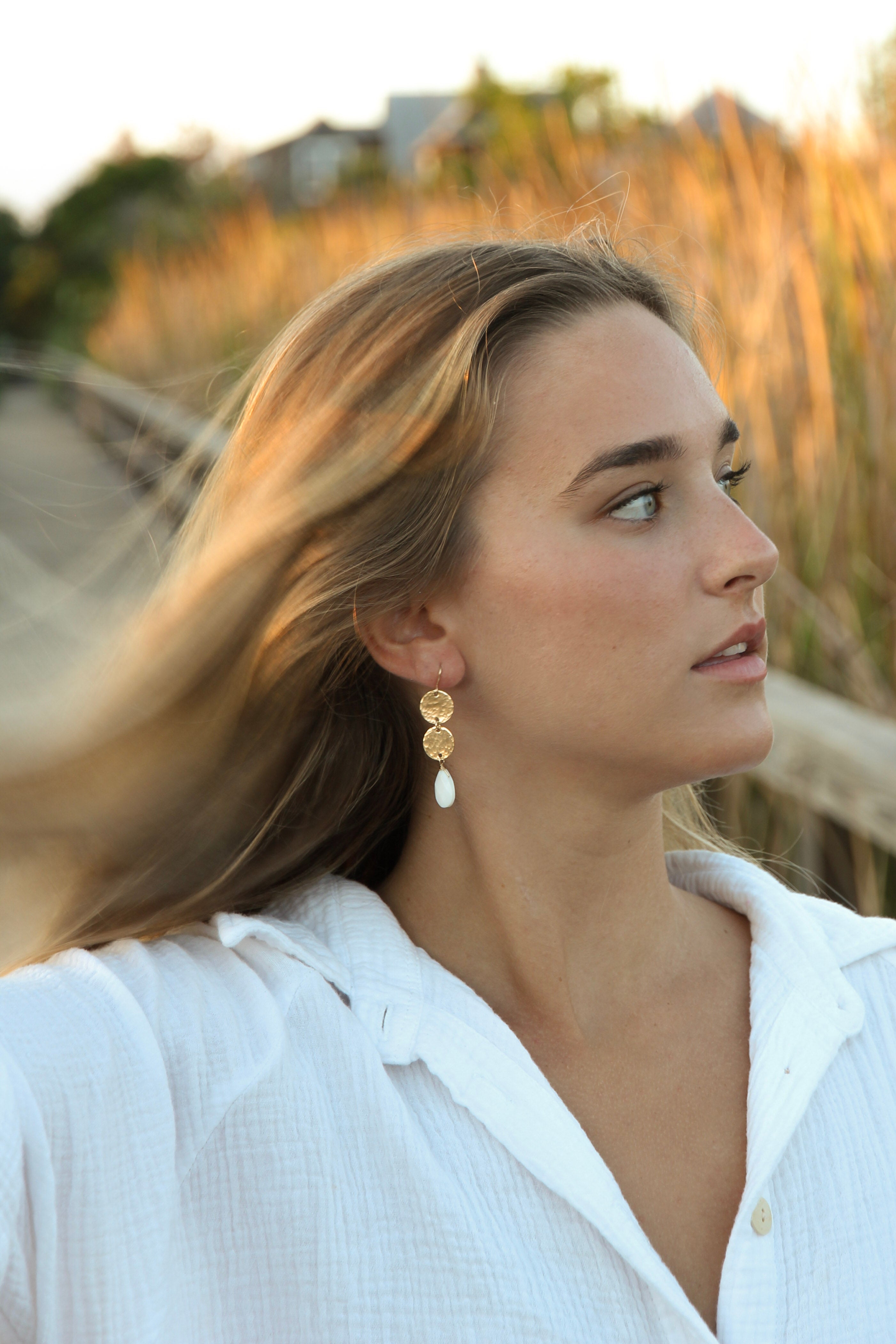 2 delicate and pretty gold hammered discs, with a faceted mother of pearl briolette hanging from the bottom. Gold filled hooks, overall length is 2 inches long. Shown in a womans ear.