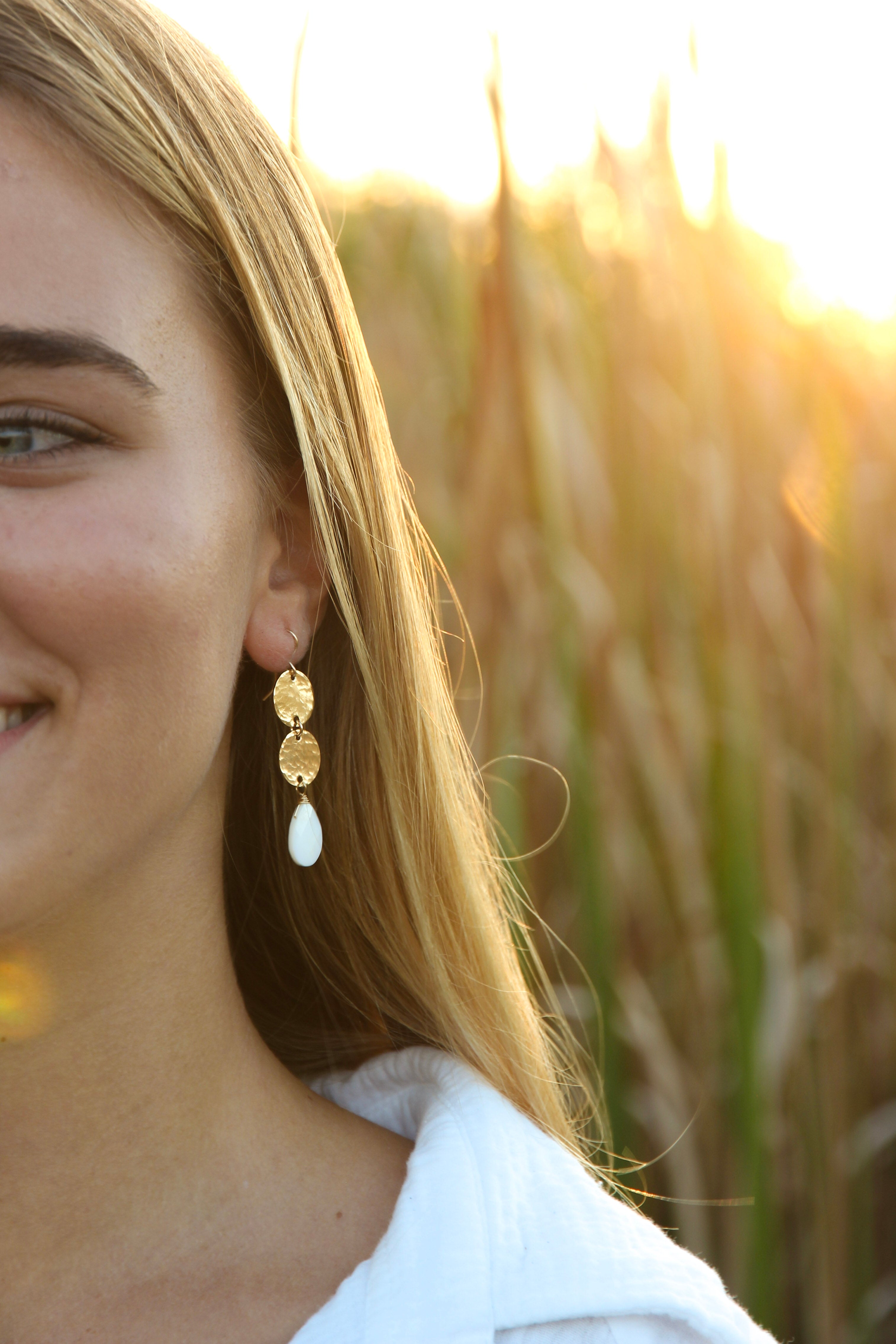2 delicate and pretty gold hammered discs, with a faceted mother of pearl briolette hanging from the bottom. Gold filled hooks, overall length is 2 inches long. Shown in a woman's ear.