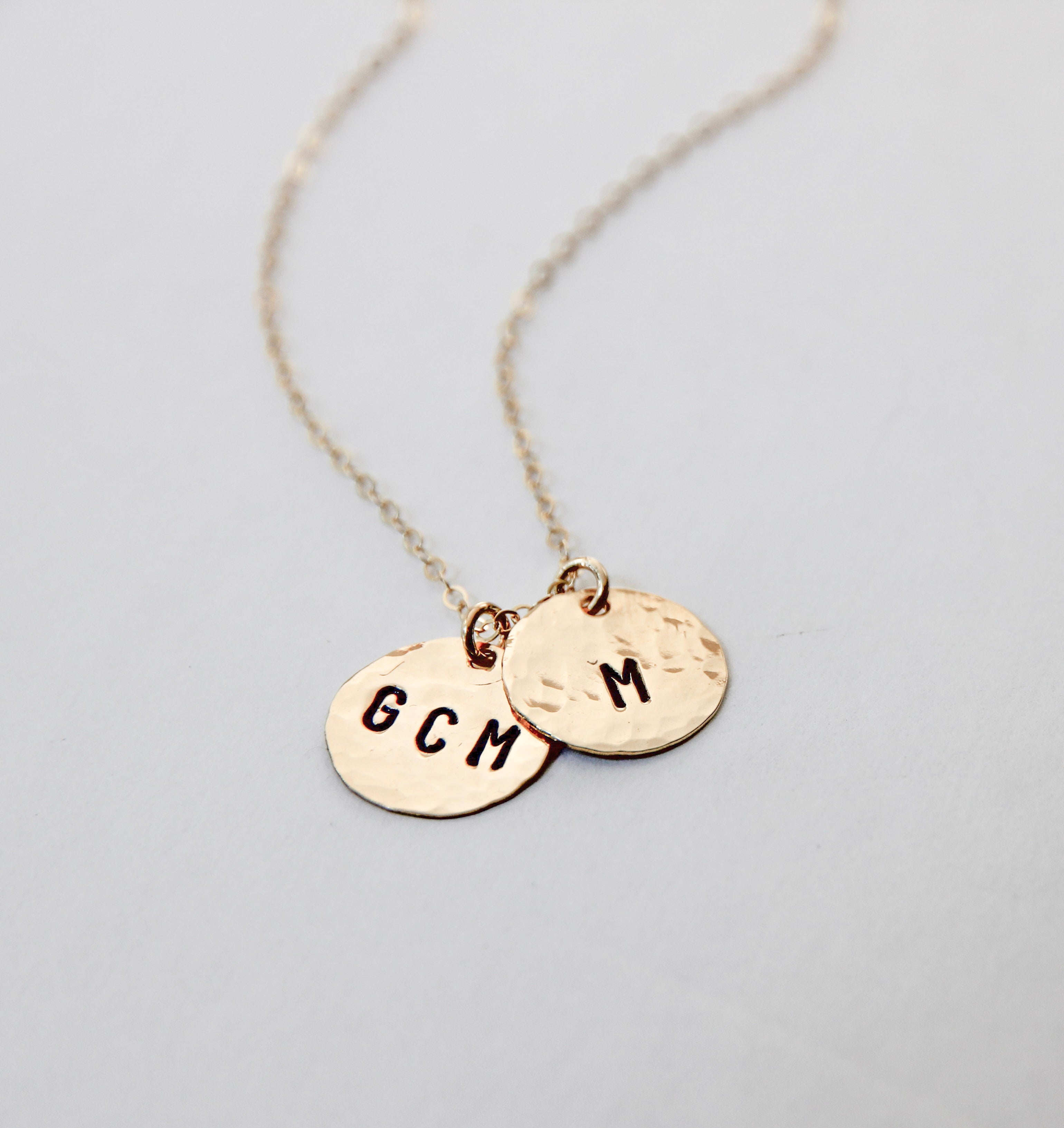 Medium size gold filled hammered circle with initials stamped onto it. On a gold chain. Shown with two charms. 