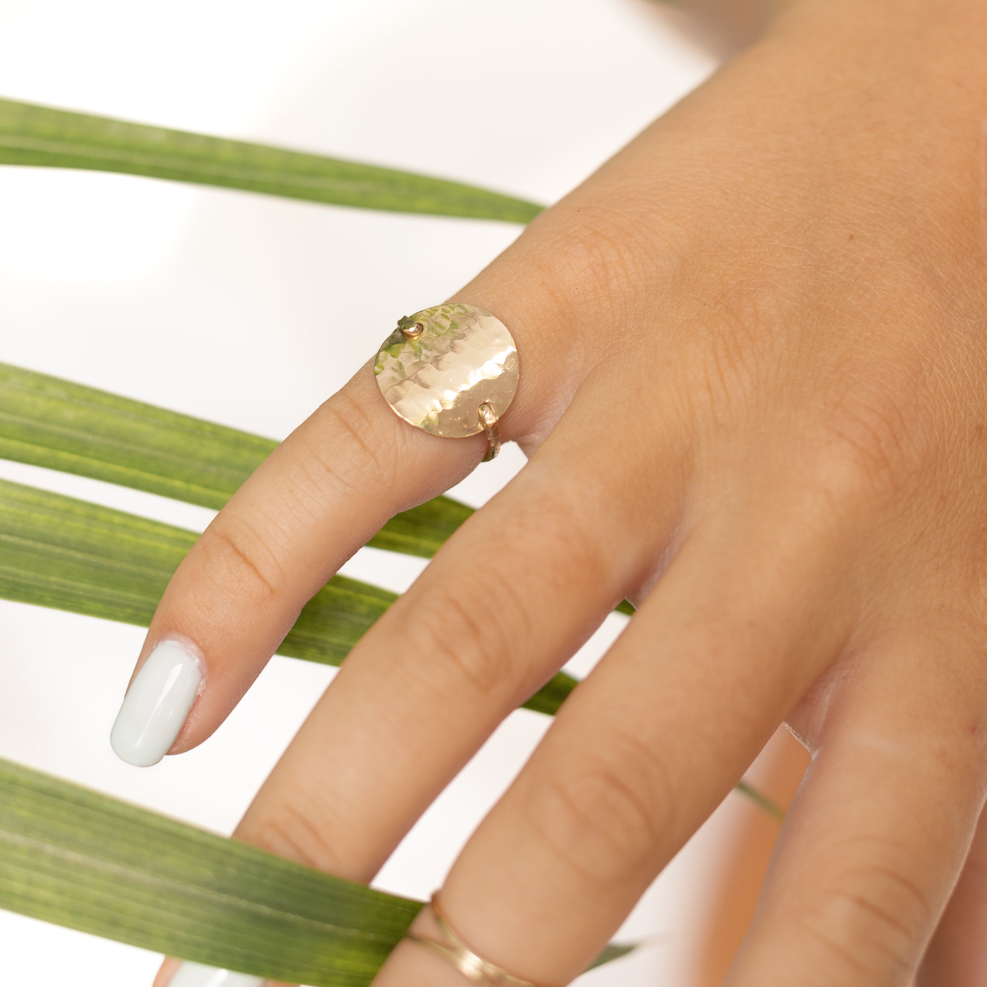 Nickel size gold filled circle hand forged into a ring with gold wire. Shown on a woman's finger. 