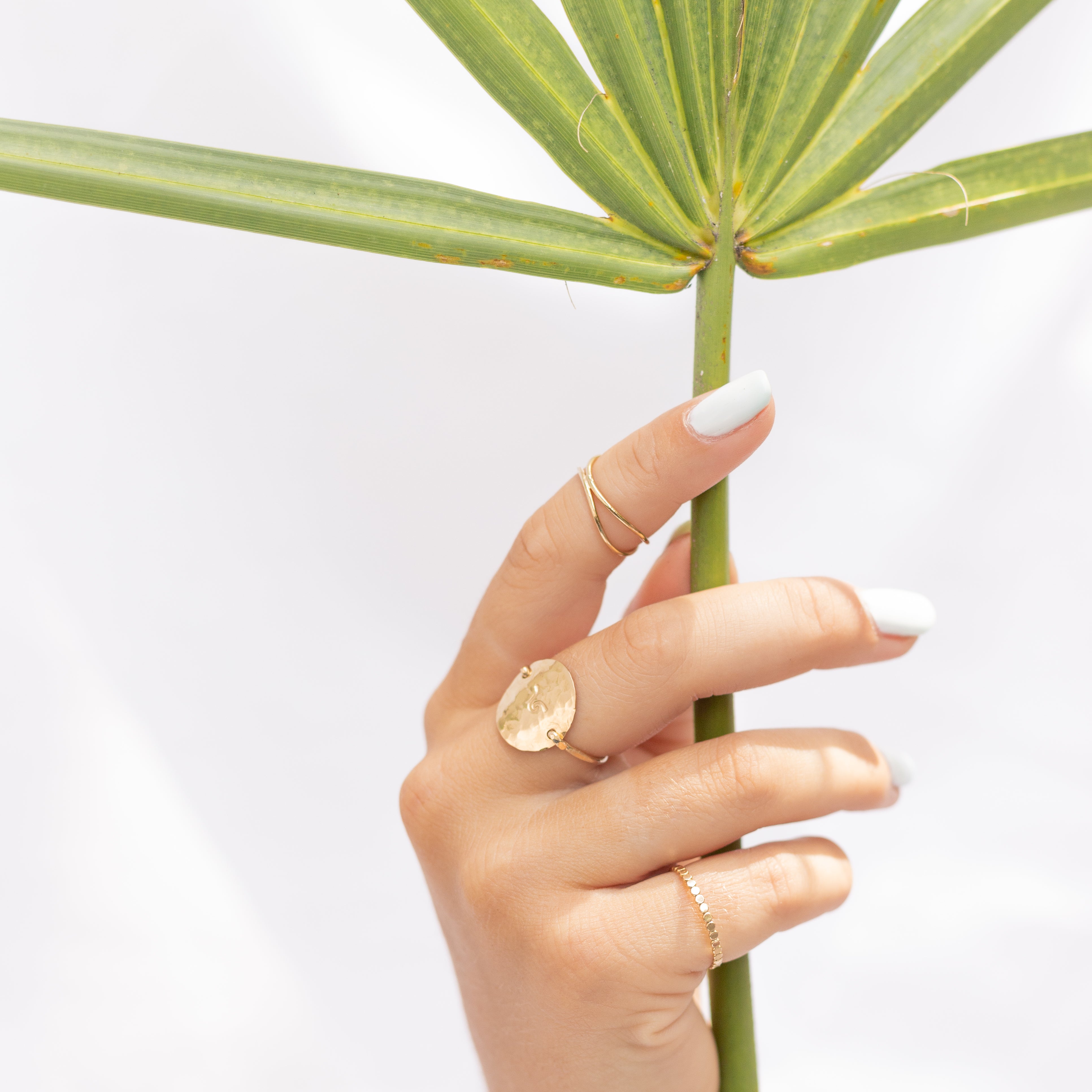 Gold-filled 1millimeter Ribbon Finger Ring shown on a hand with other rings. It is shown on the pointer finger.