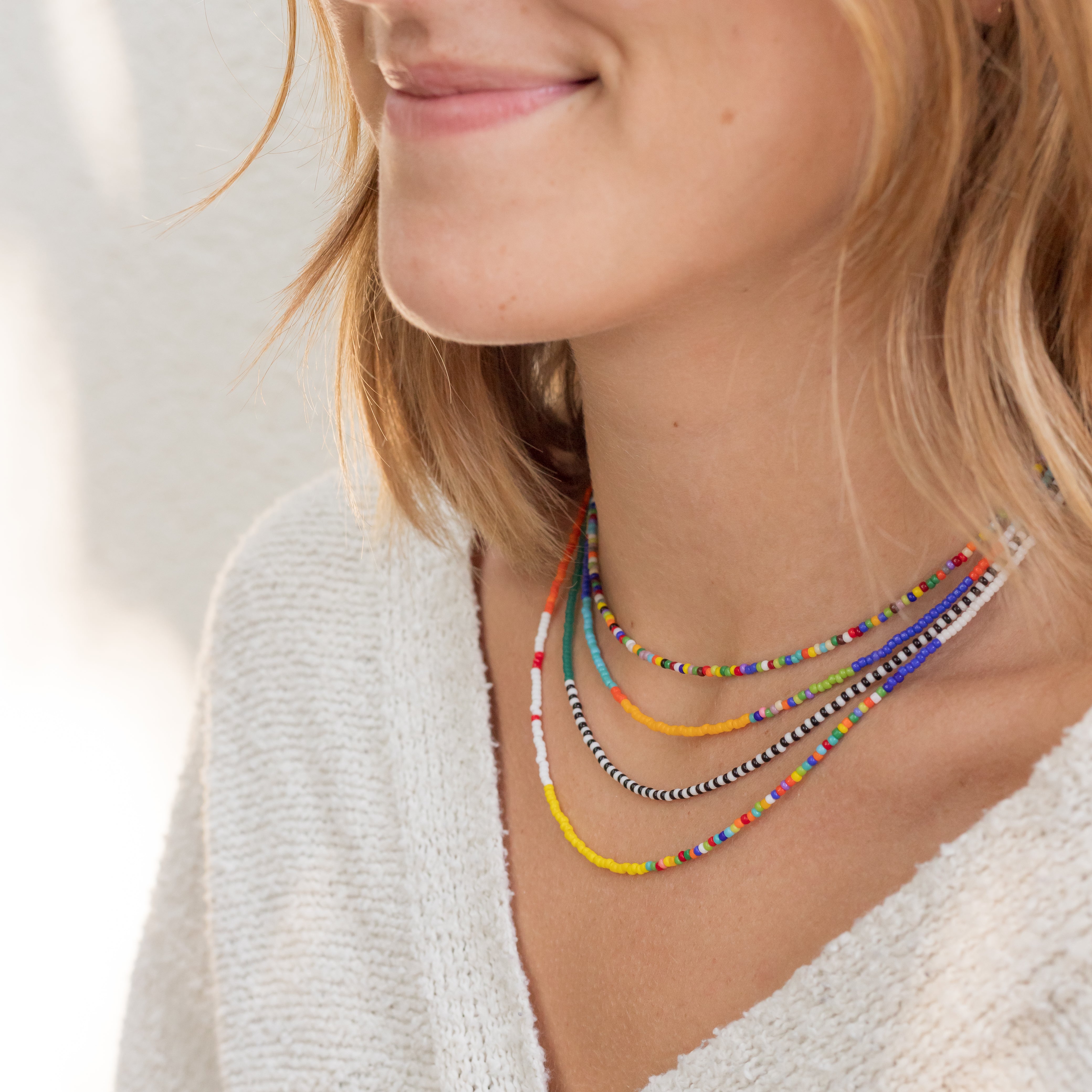 The four different seed bead necklaces on a woman's neck