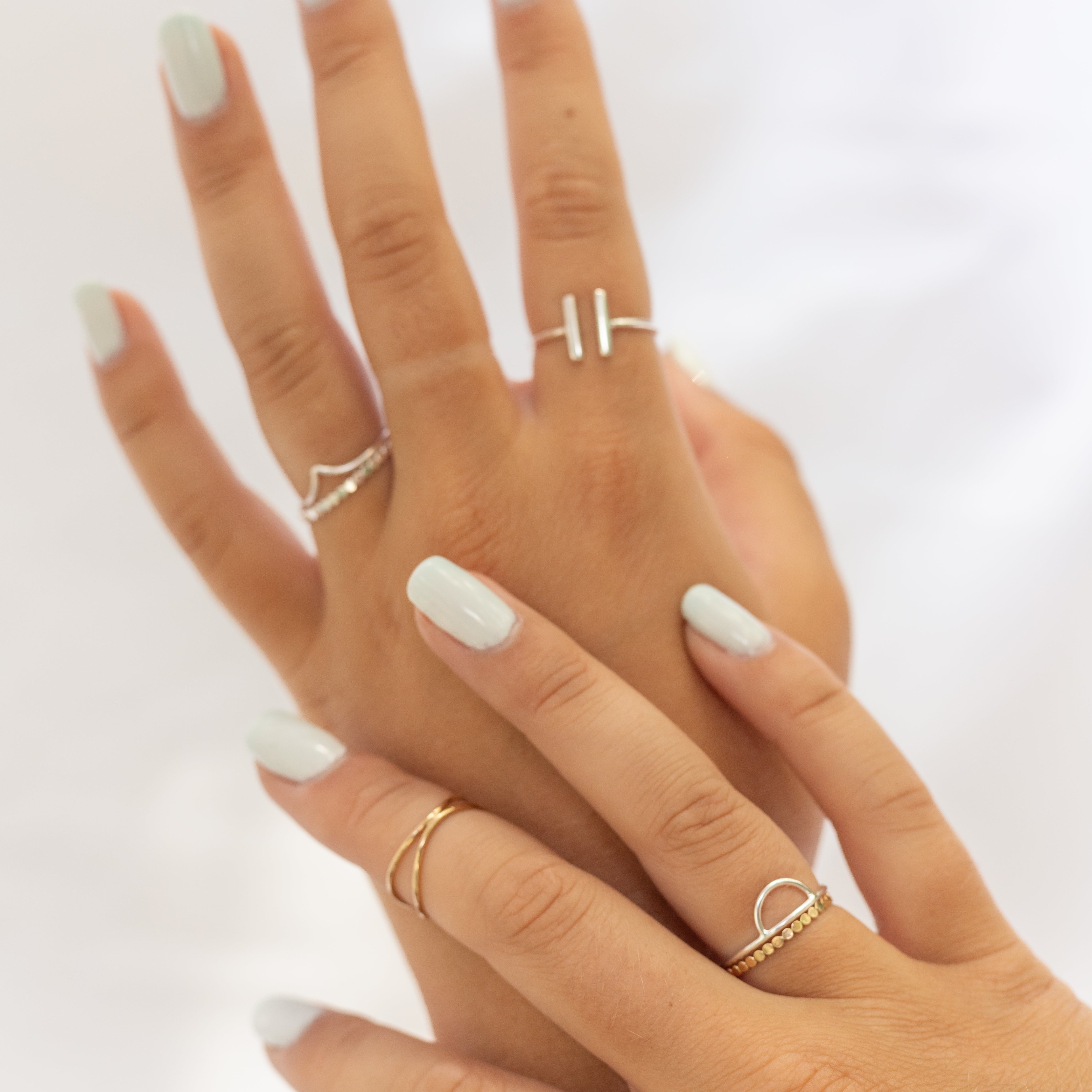 Sterling silver ring with a curve at the top, displayed on a woman's hand with several other rings