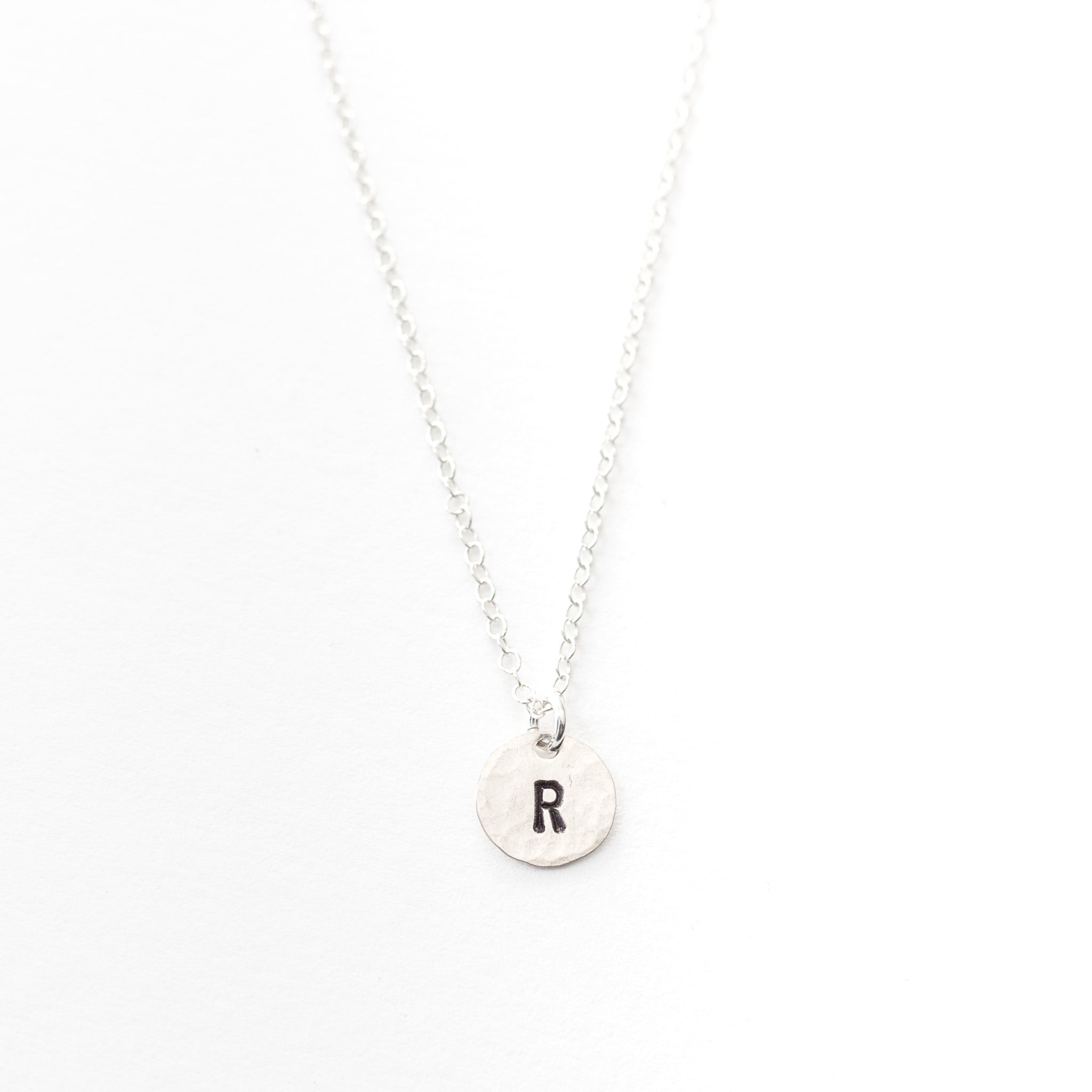 Tiny sterling silver circle with initials stamped onto it. On a silver chain.