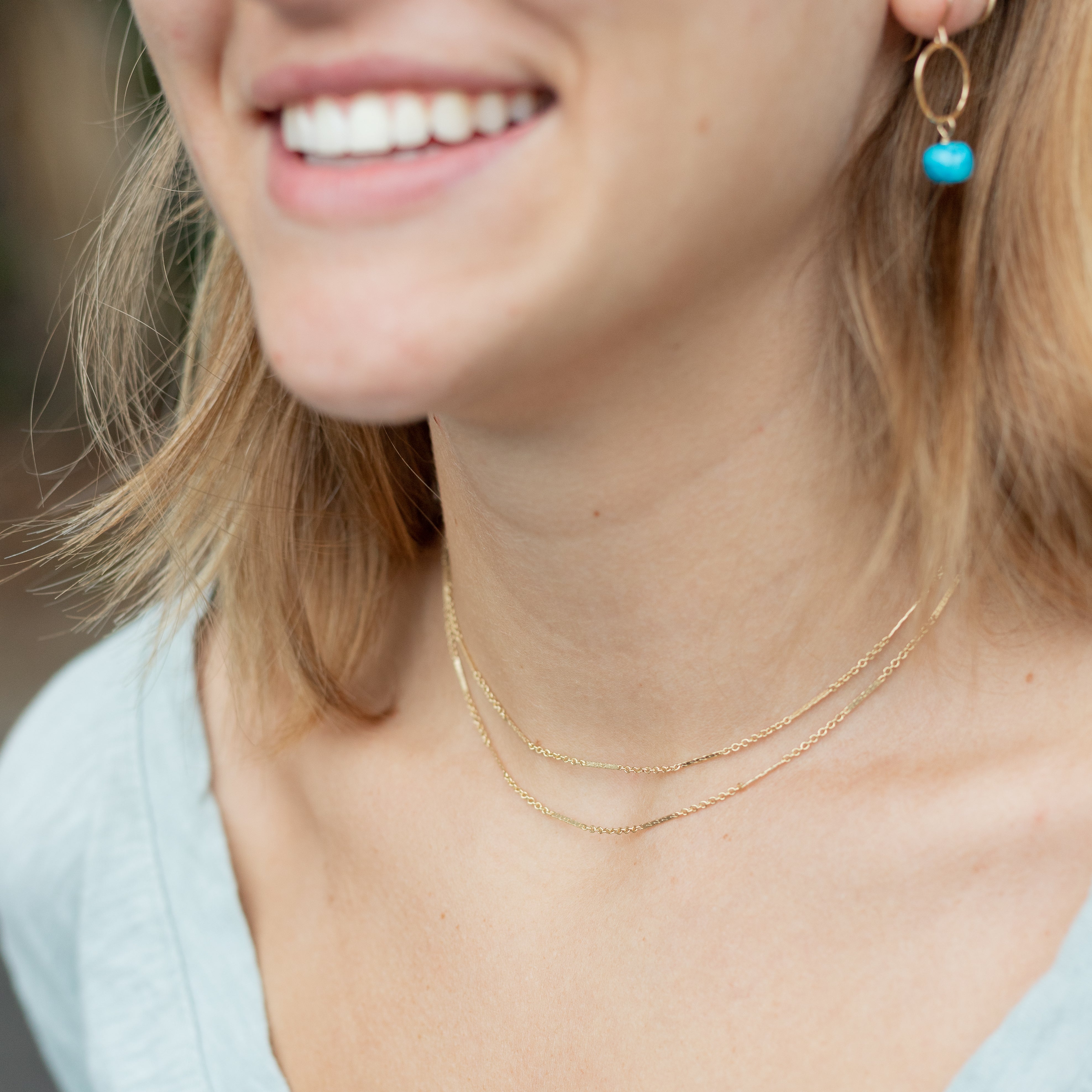 Dainty gold thin necklace that wraps around your neck two times. Displayed on a woman's neck. 