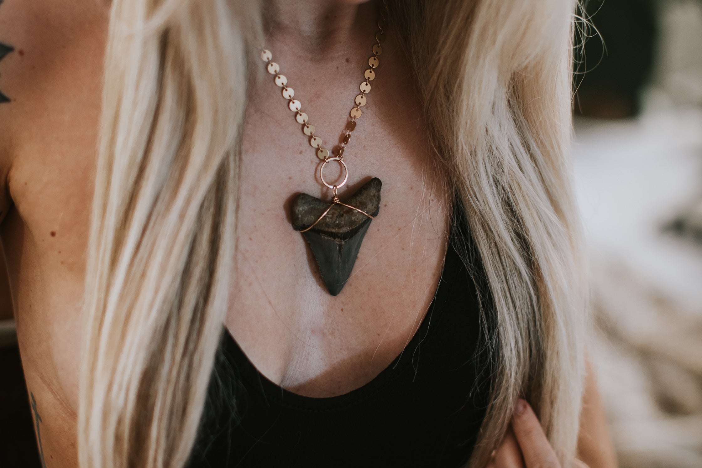 megalodon tooth wire wrapped and on a gold circle and gold circle chain. Shown on a woman.